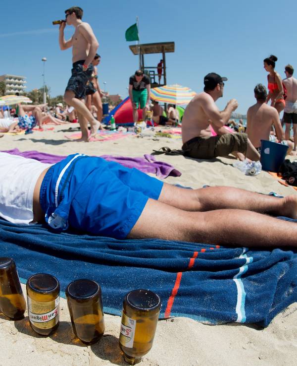 Ein deutscher Tourist liegt am 06.06.2013 schlafend auf einer Luftmatratze neben leeren Bierflaschen am Strand von Arenal auf der Mittelmeerinsel Mallorca.