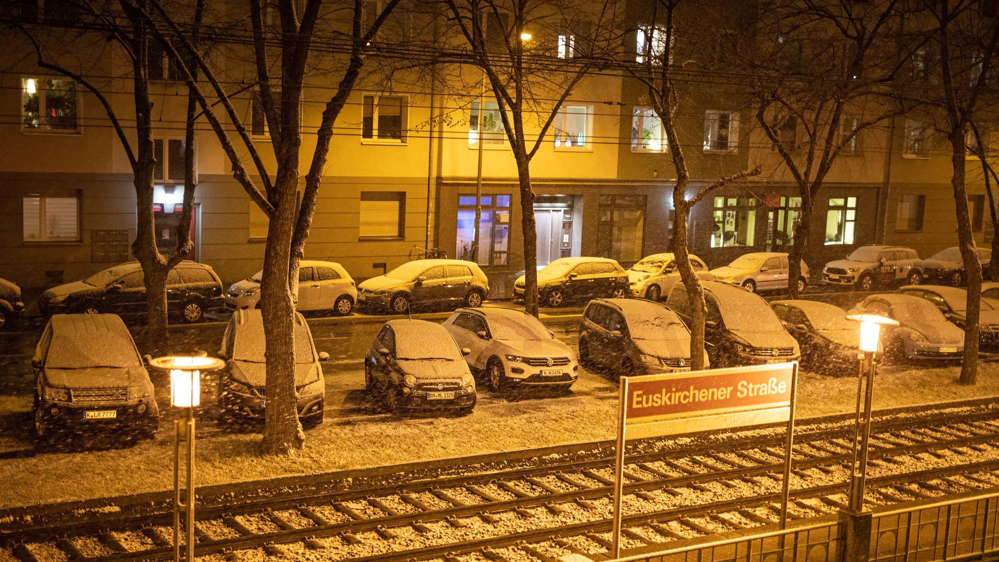 Foto von oben zeigt schneebedeckte Autos an einer KVB-Haltestelle in Köln.