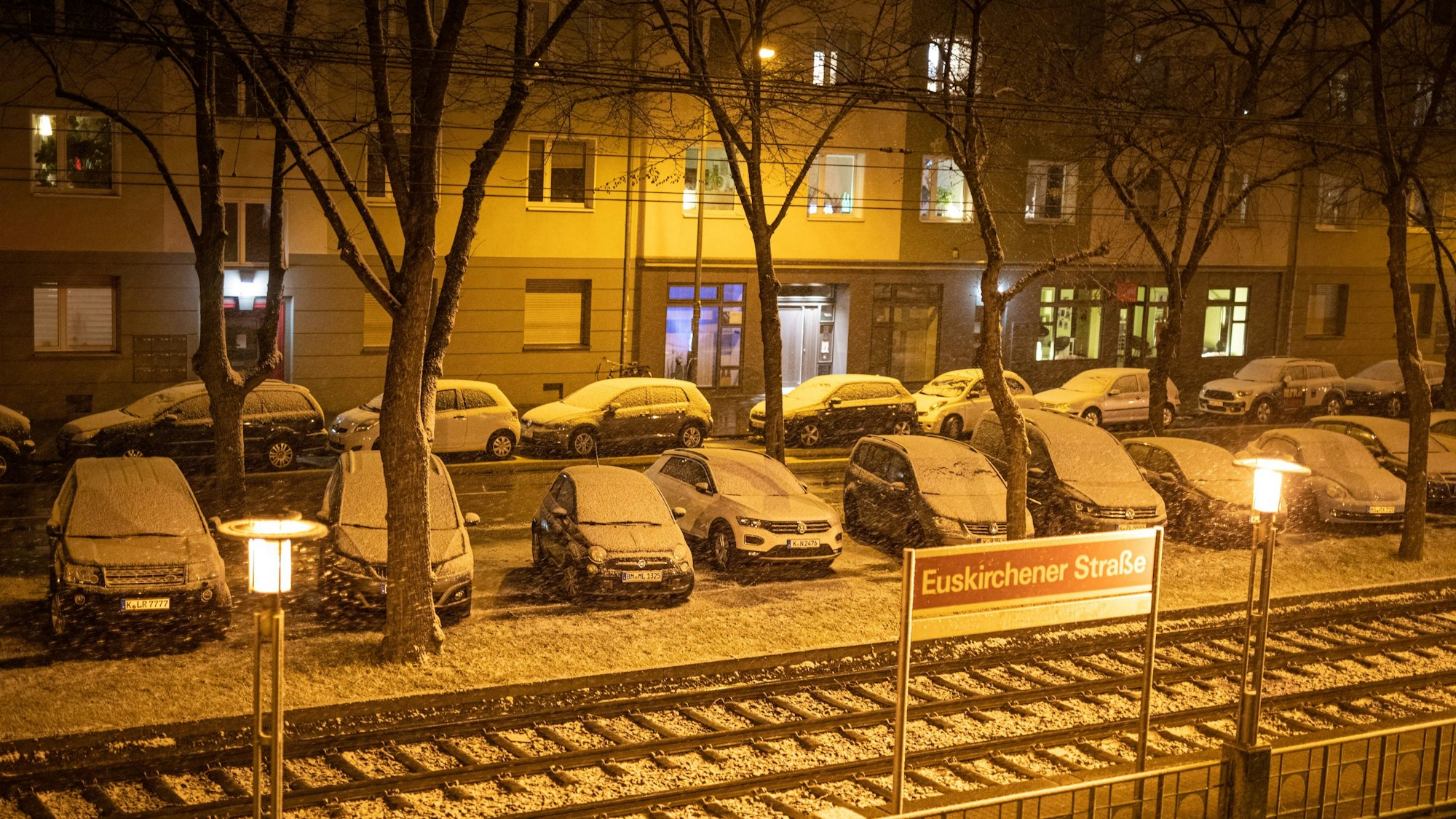 Foto von oben zeigt schneebedeckte Autos an einer KVB-Haltestelle in Köln.