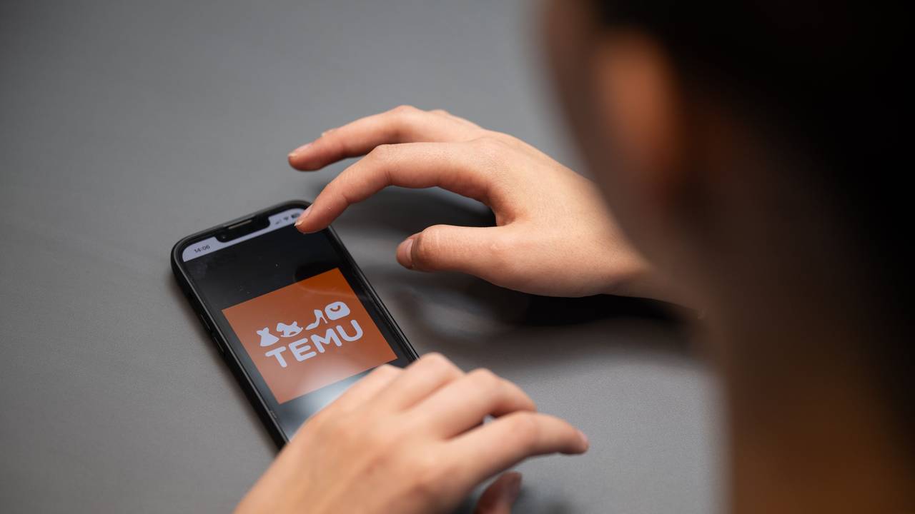 Eine Person hält ein Telefon mit der App Temu in den Händen, hier im August 2023 in Berlin.