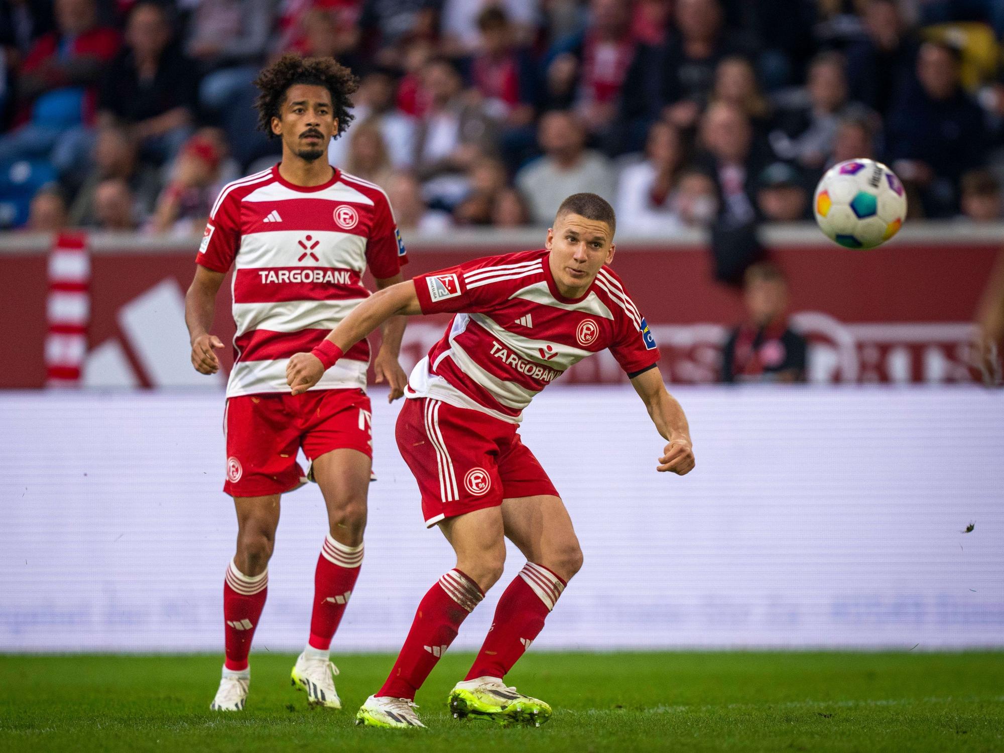 Emmanuel Iyoha und Christos Tzolis schauen den Ball an.