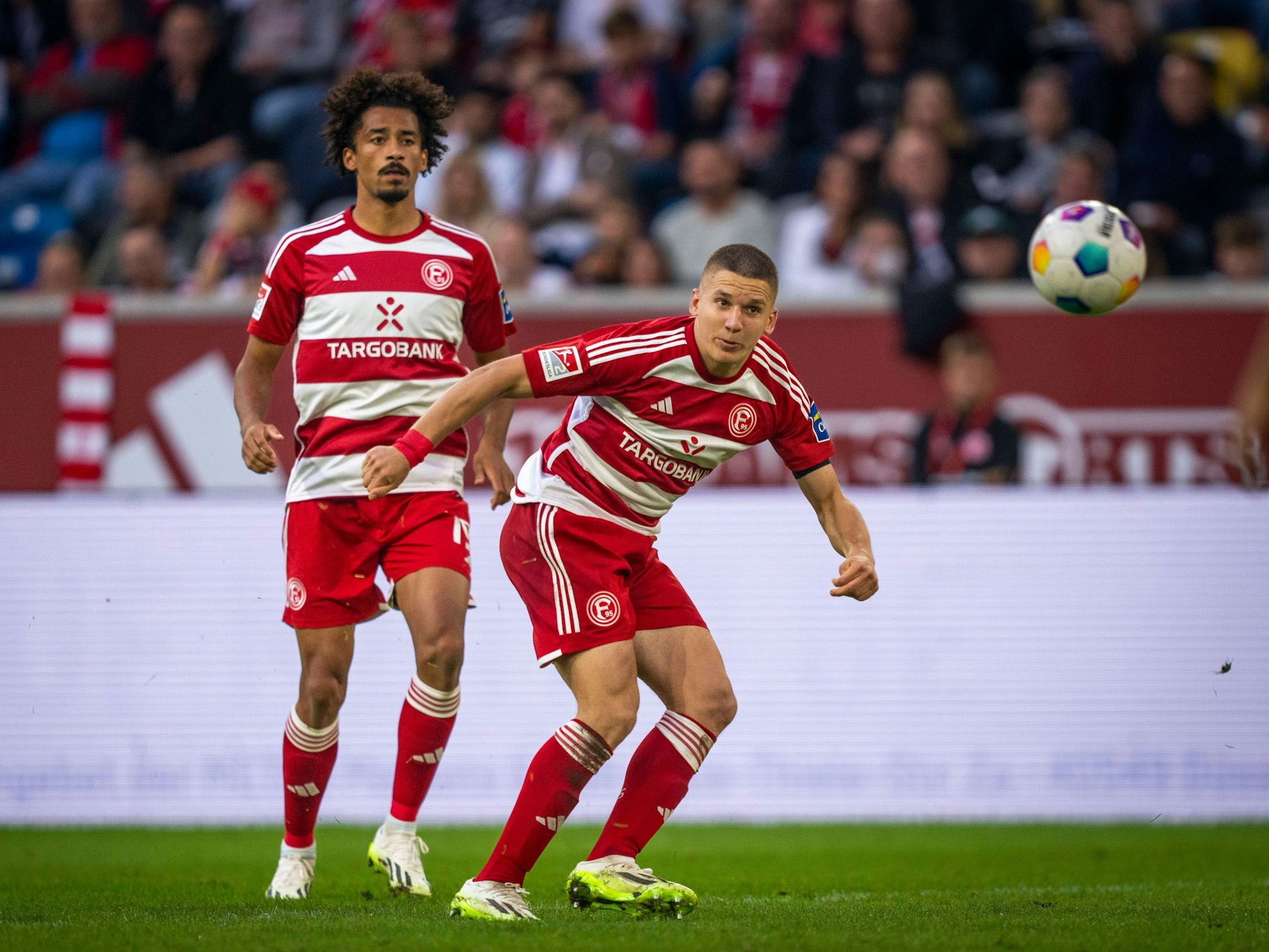 Emmanuel Iyoha und Christos Tzolis schauen den Ball an.