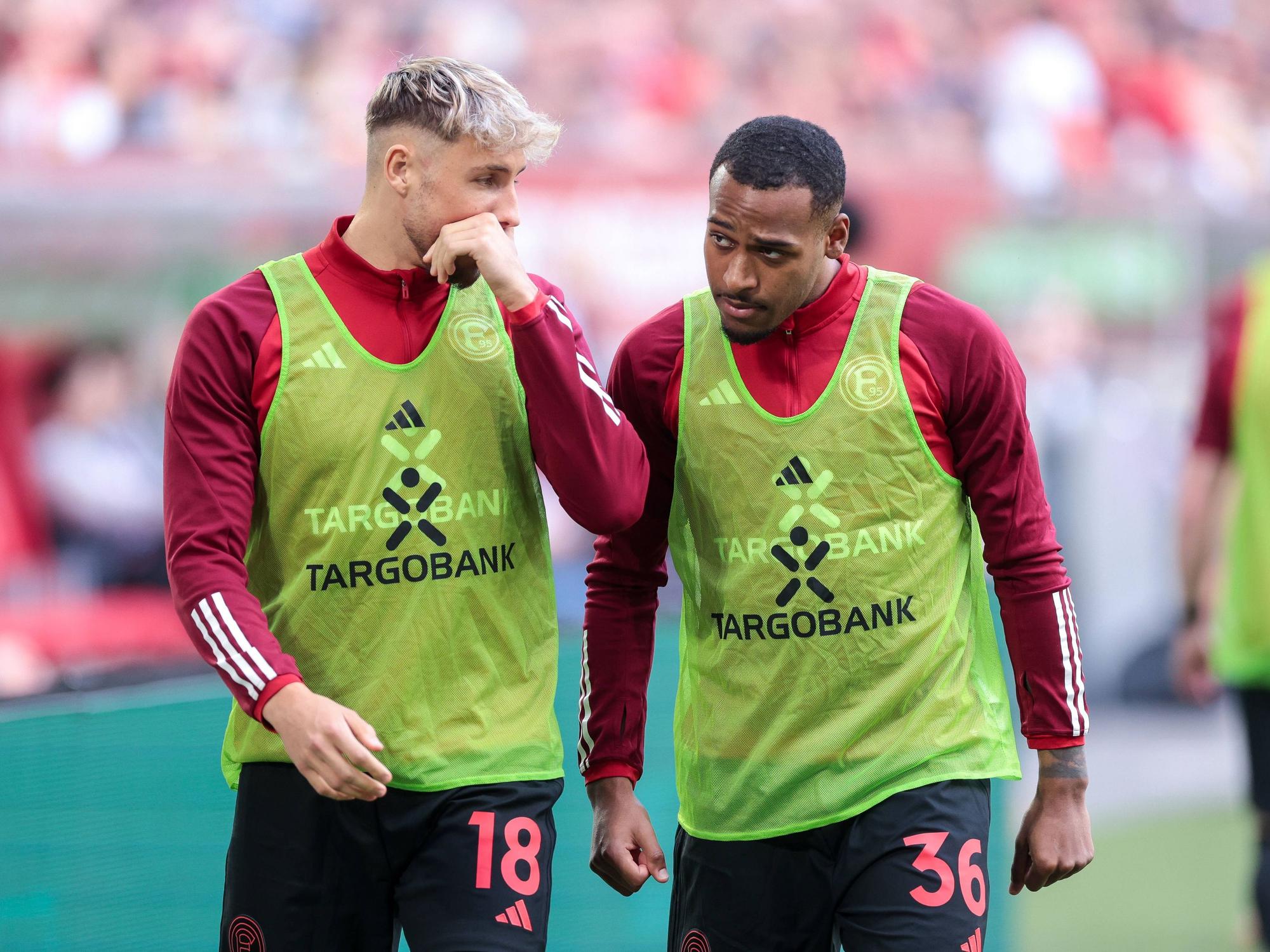 Die Düsseldorf-Profis Jona Niemiec und Marlon Mustapha unterhalten sich beim Aufwärmen am Seitenrand.