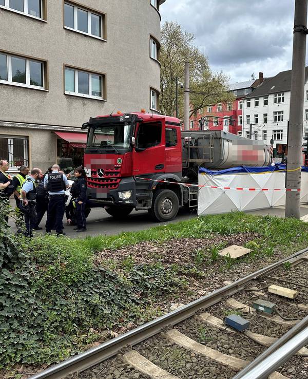 Ein Lkw steht auf einer Straße, an seiner Seite ein Sichtschutz. Die Polizei hat den Bereich abgesperrt.
