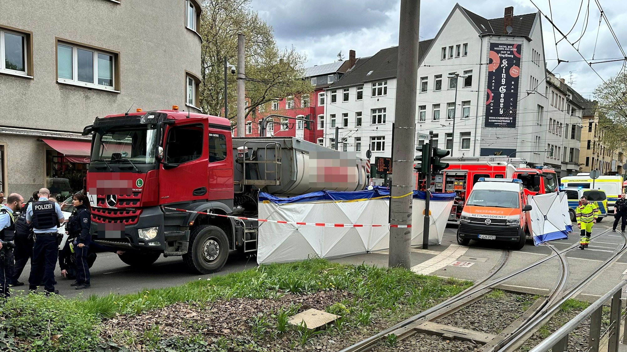 Ein Lkw steht auf einer Straße, an seiner Seite ein Sichtschutz. Die Polizei hat den Bereich abgesperrt.