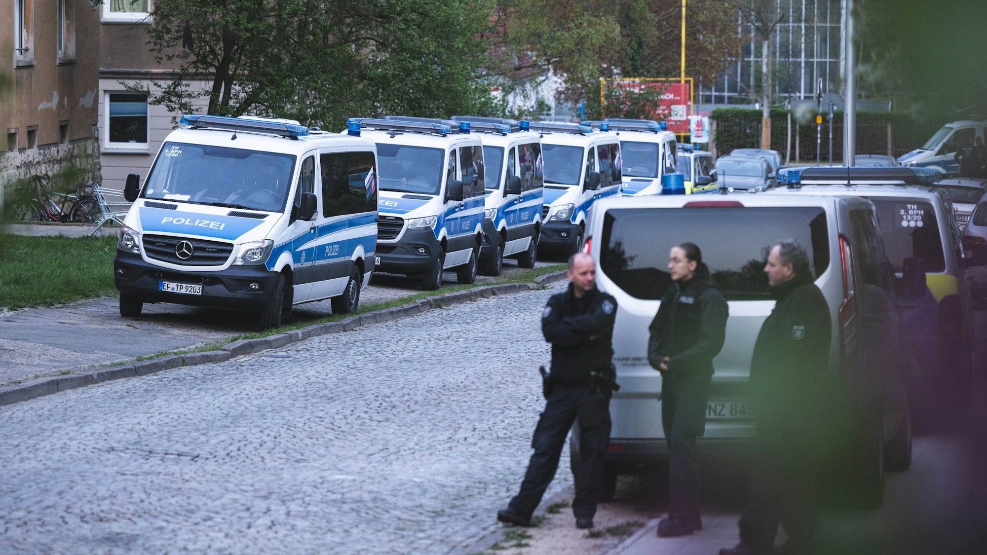 Einsatzkräfte der Polizei und mehrere Einsatzfahrzeuge stehen in einer Straße.