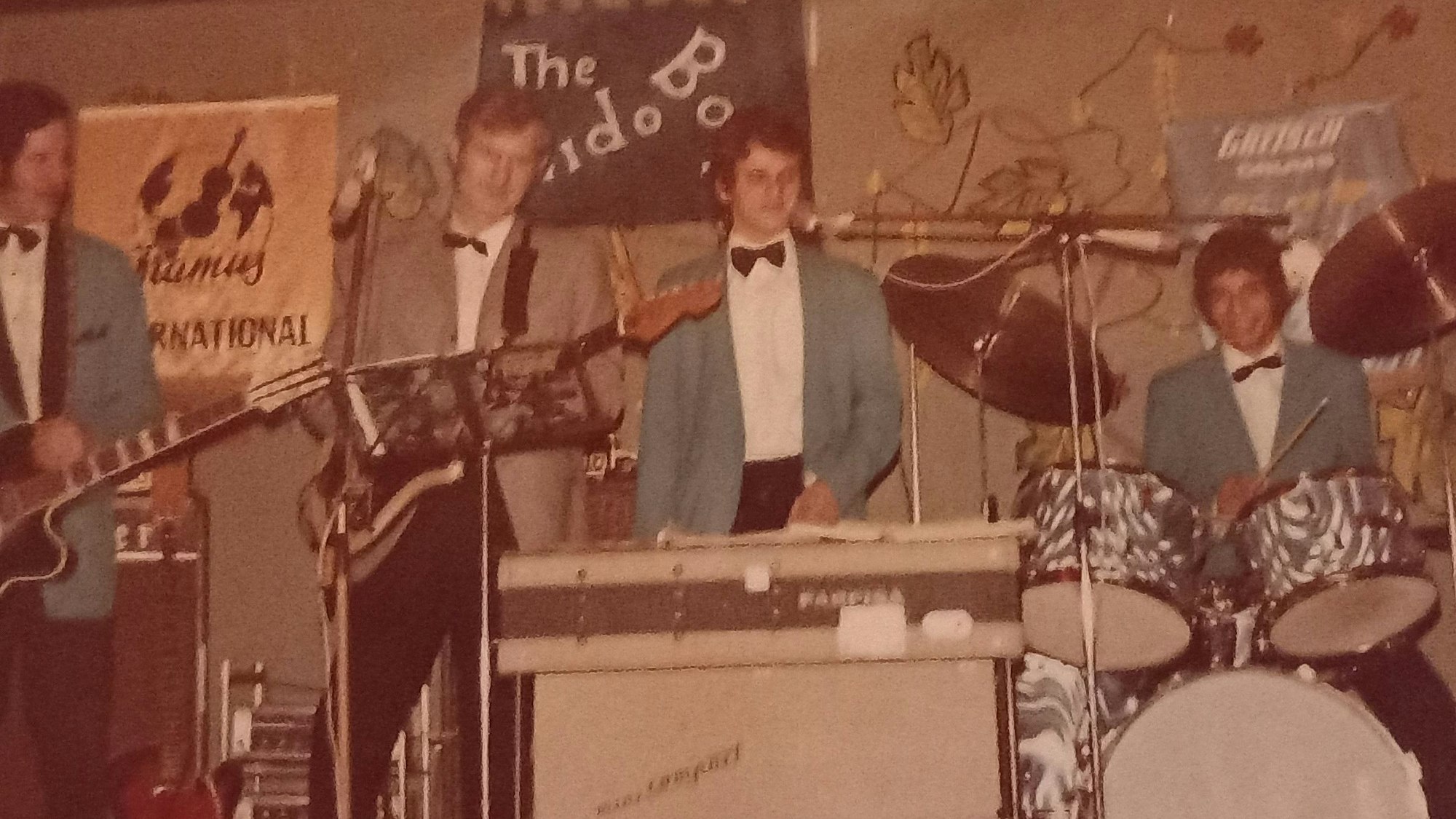 Eine Band besteht aus vier jungen Männern, die Anzug und Fliege tragen.