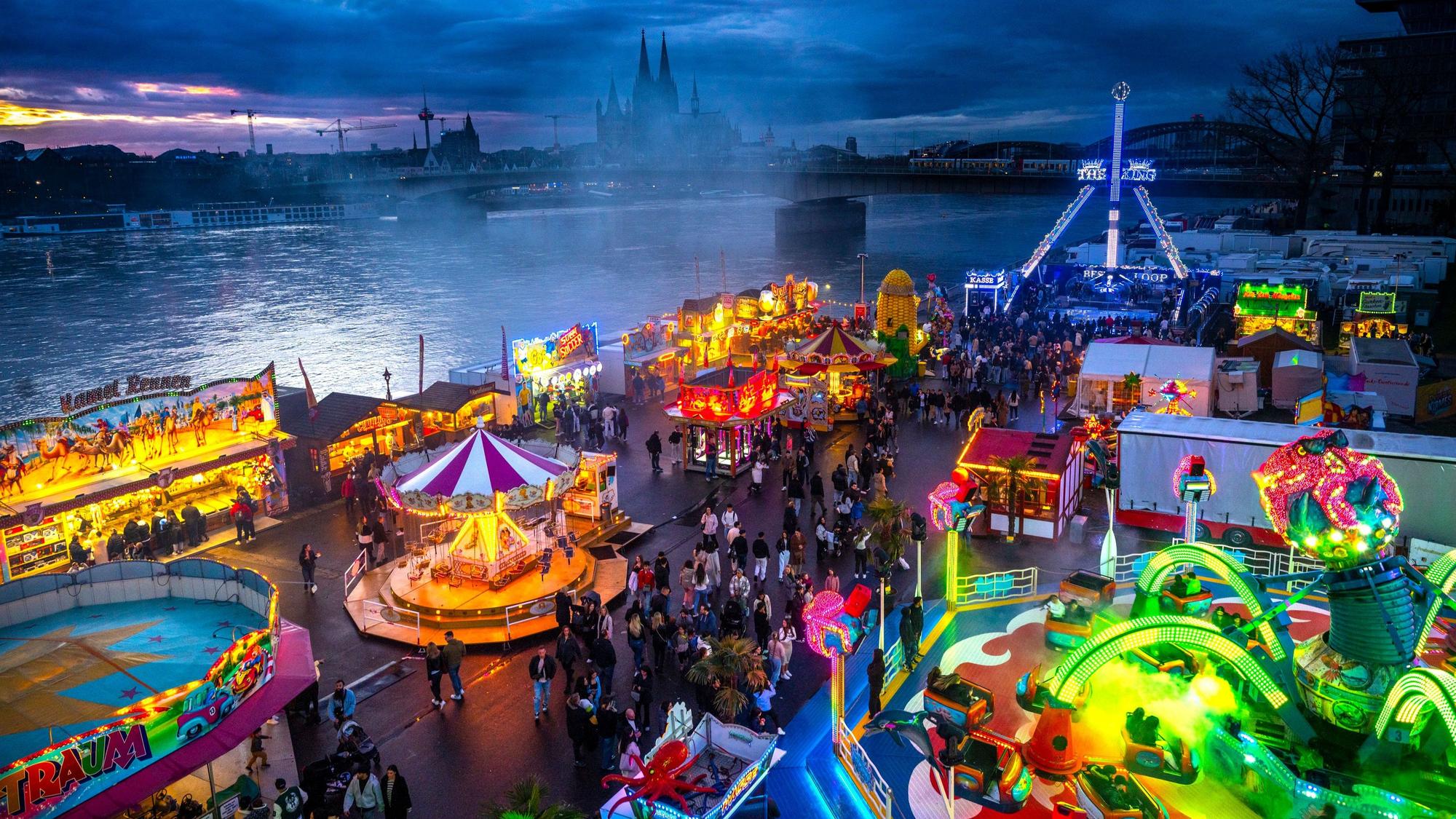 Die Deutzer Kirmes leuchtet in der Abenddämmerung.