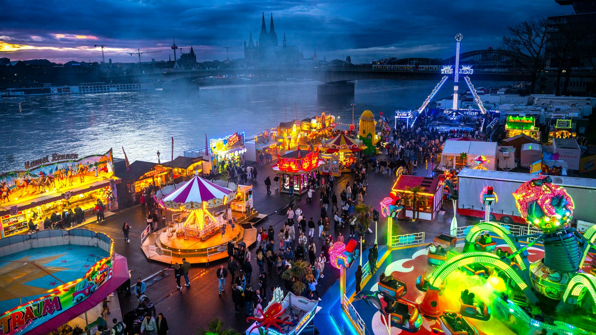 Die Deutzer Kirmes leuchtet in der Abenddämmerung.