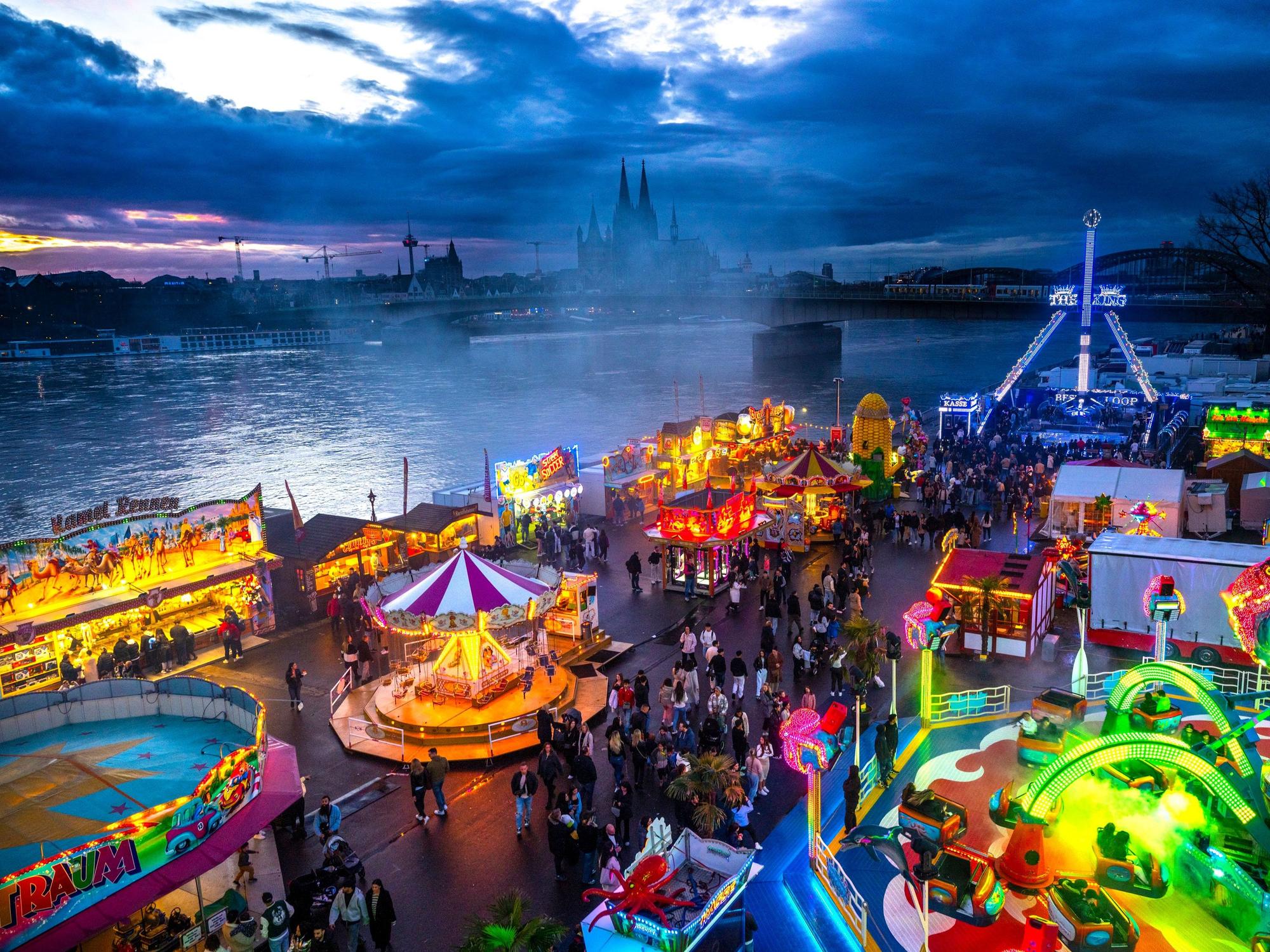 Die Deutzer Kirmes leuchtet in der Abenddämmerung.