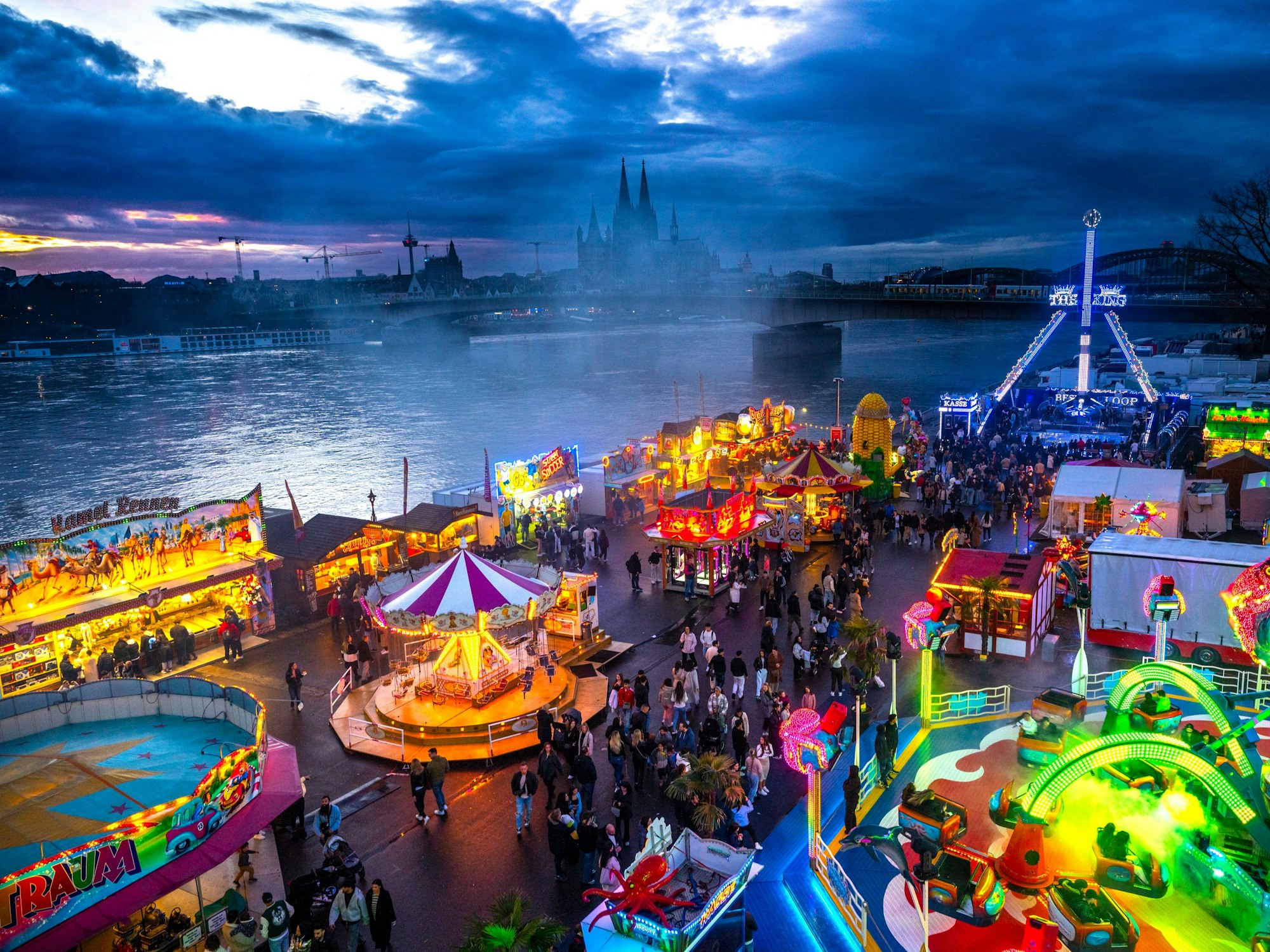 Die Deutzer Kirmes leuchtet in der Abenddämmerung.