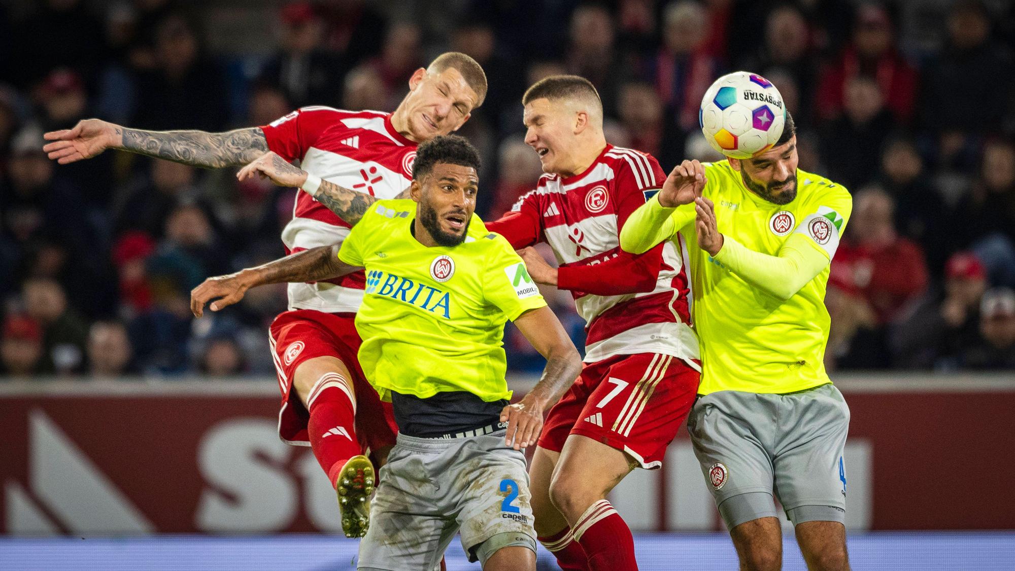 Jordy de Wijs und Christos Tzolis im Kopfball-Duell mit zwei Wiesbaden-Spielern.