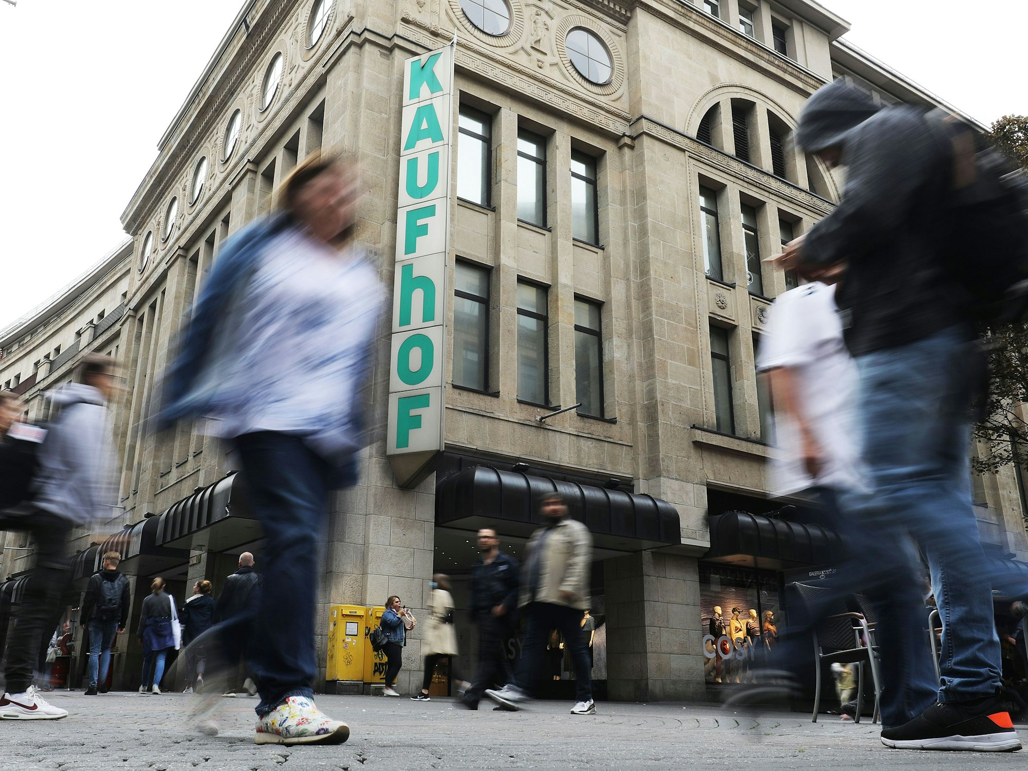 Menschen gehen an einer Kaufhof-Filiale vorbei.