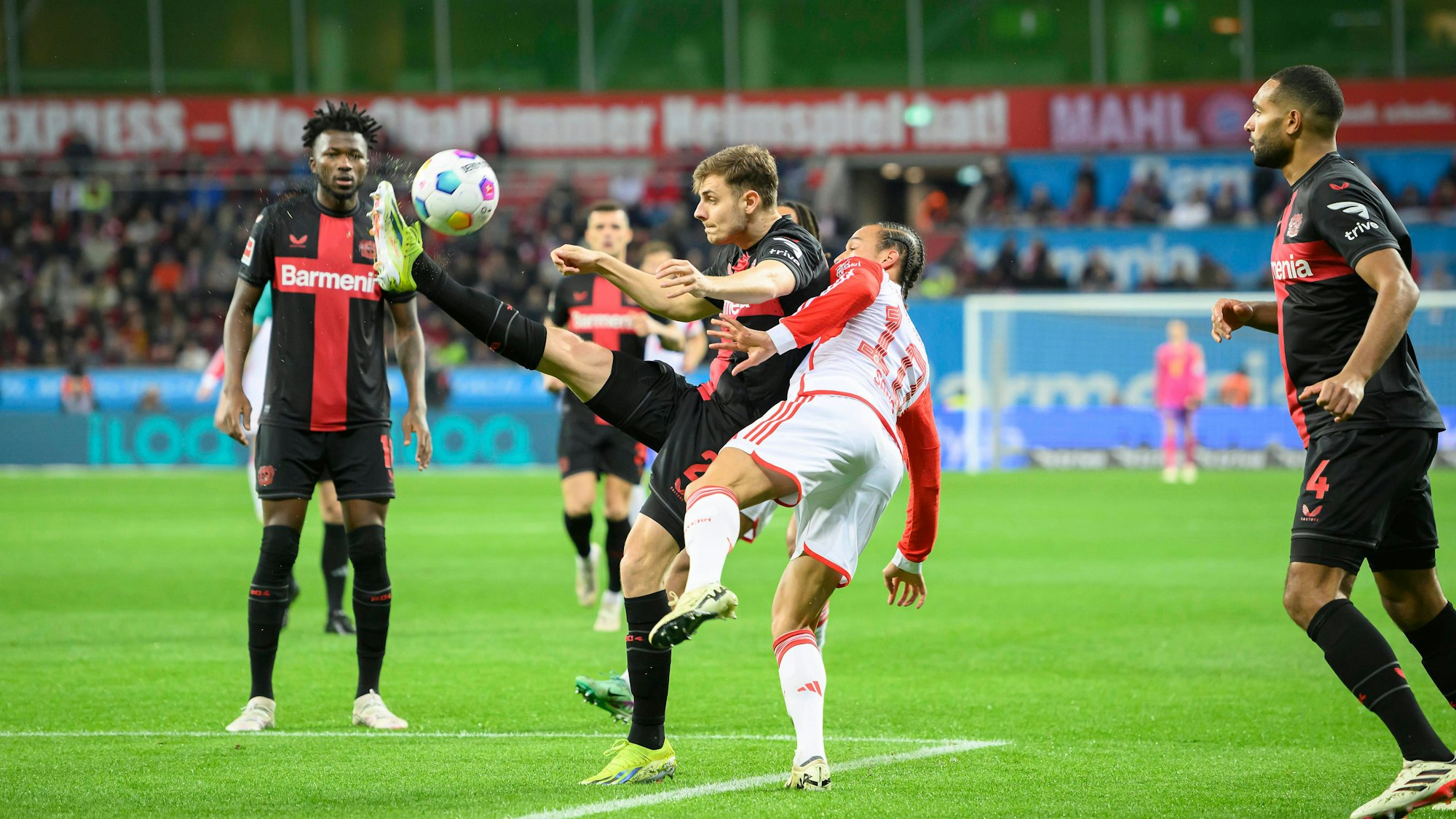 Josip Stanisic (Leverkusen) in einem Zweikampf mit Leroy Sané (FC Bayern München).