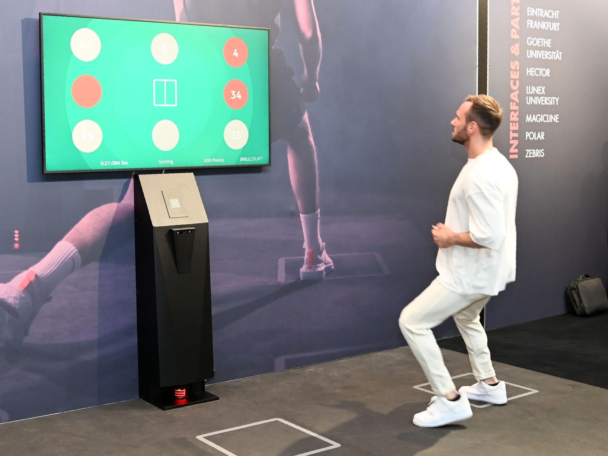 Personal Trainer Manuel Gajus springt mit Blick auf einen Bildschirm auf dem Skillcourt herum.