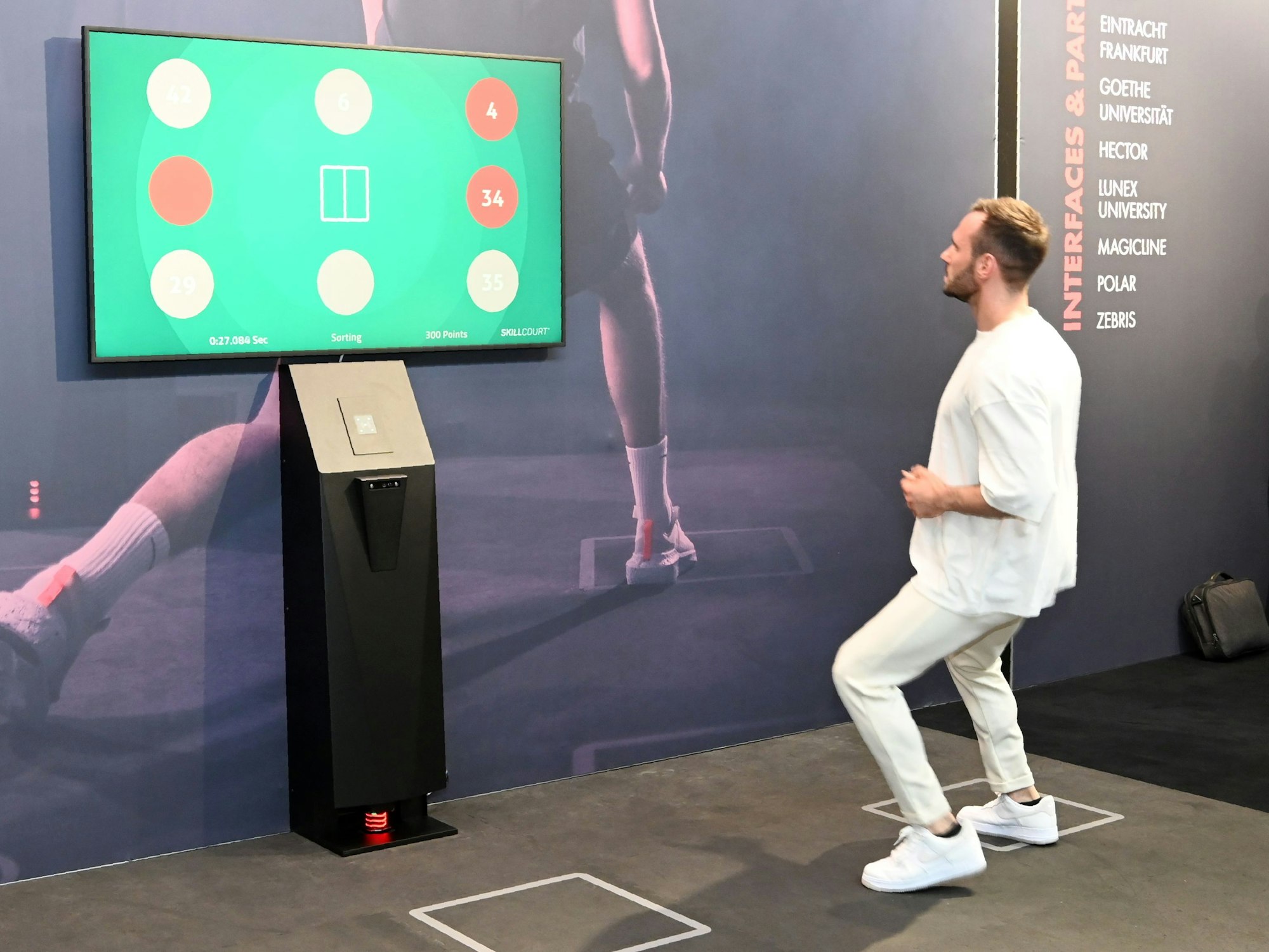 Personal Trainer Manuel Gajus springt mit Blick auf einen Bildschirm auf dem Skillcourt herum.