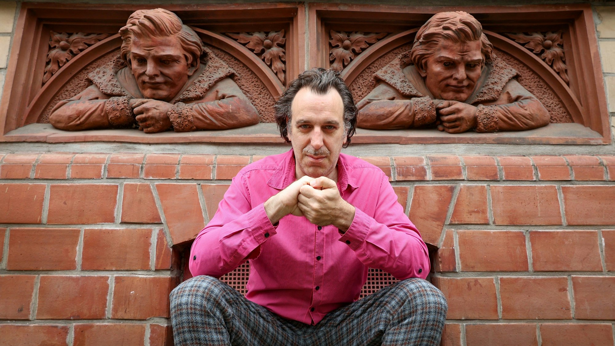 Der Musiker Chilly Gonzales sitzt vor einem Haus.