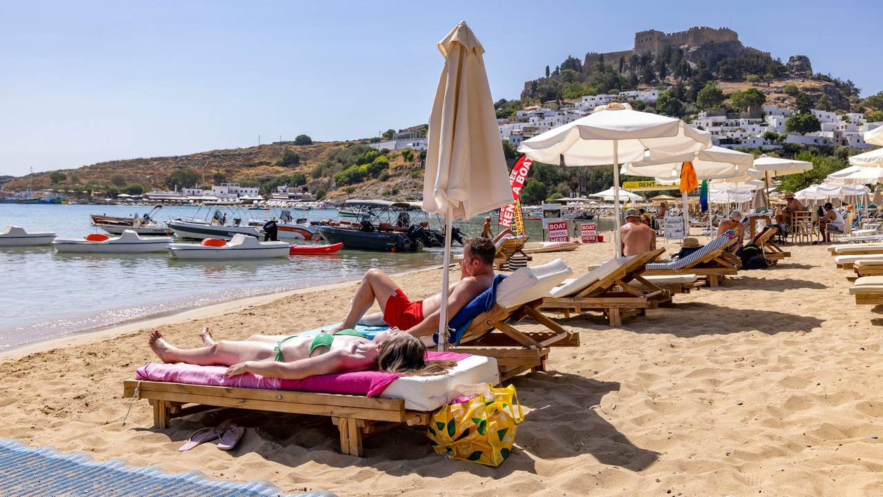 Am Strand in Lindos, etwa 10 Kilometer von den Bränden im Südosten entfernt, sind weiterhin Touristen am Strand, im Hintergrund die weltbekannte Akropolis von Lindos.