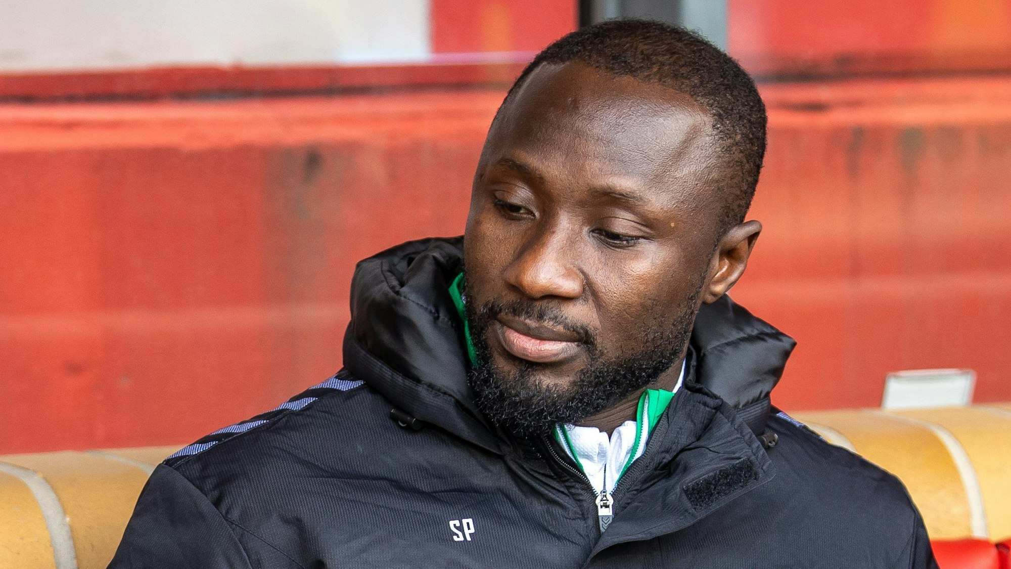 Naby Keita von Werder Bremen sitzt auf der Bank und blickt nach unten.