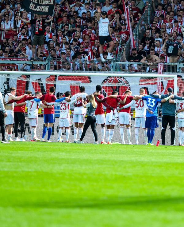 Die Mannschaft von Fortuna Düsseldorf steht nach dem Sieg in Wiesbaden vor den mitgereisten Fans.