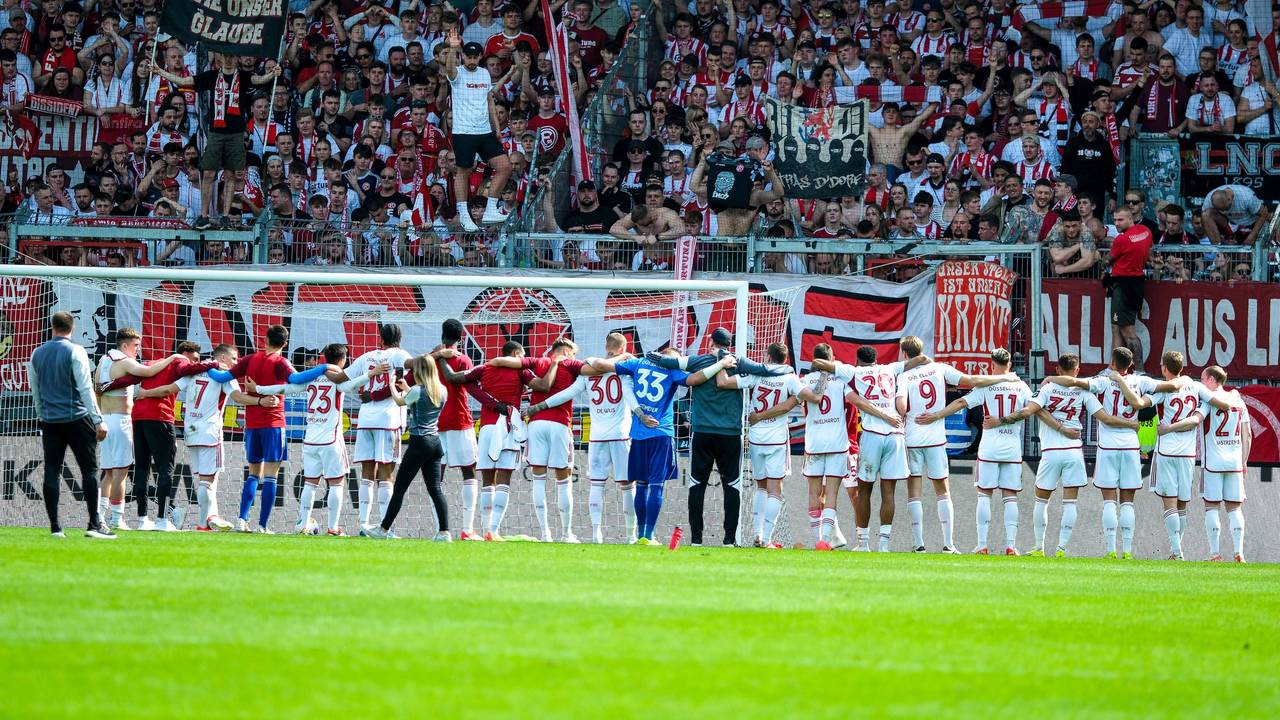 Die Mannschaft von Fortuna Düsseldorf steht nach dem Sieg in Wiesbaden vor den mitgereisten Fans.