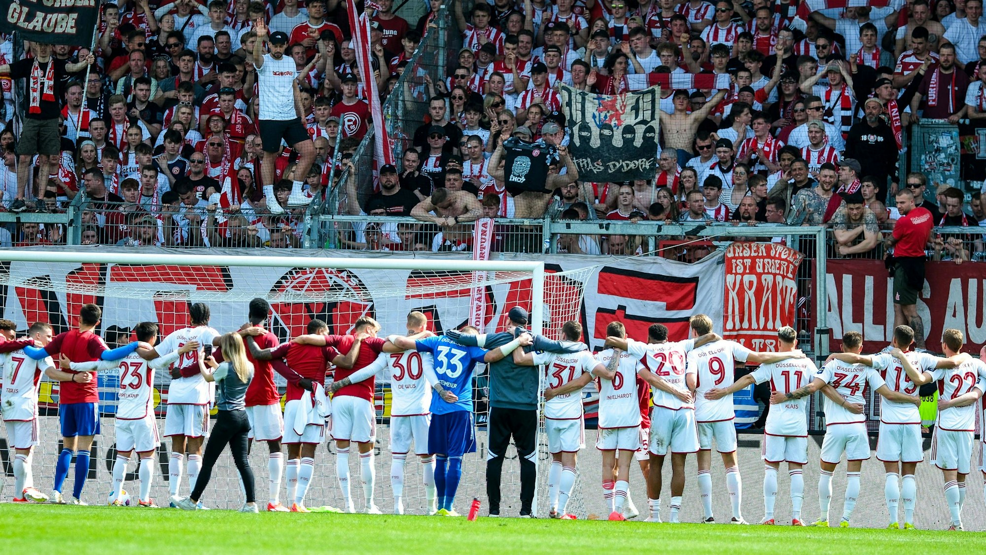 Die Mannschaft von Fortuna Düsseldorf steht nach dem Sieg in Wiesbaden vor den mitgereisten Fans.