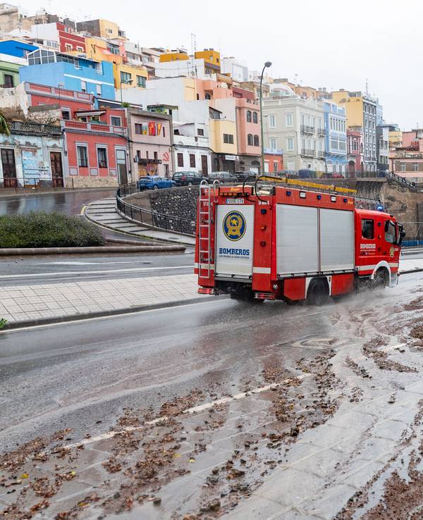 Ein Feuerwehrauto fährt nach Regen eine schlammige Straße entlang.