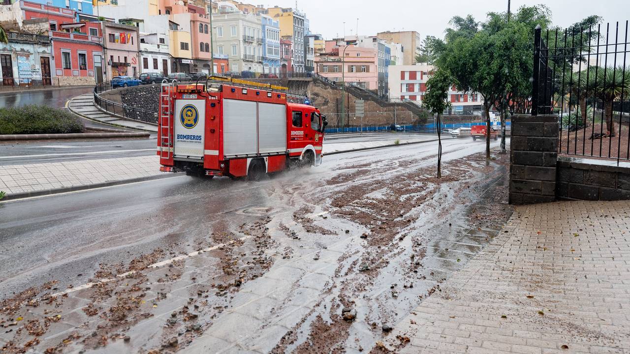 Ein Feuerwehrauto fährt nach Regen eine schlammige Straße entlang.