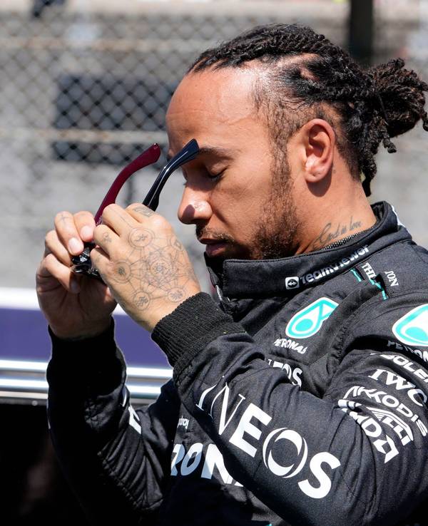 Lewis Hamilton setzt sich eine Sonnenbrille auf.