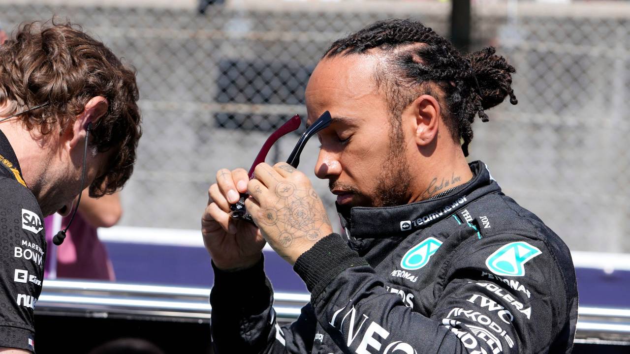 Lewis Hamilton setzt sich eine Sonnenbrille auf.