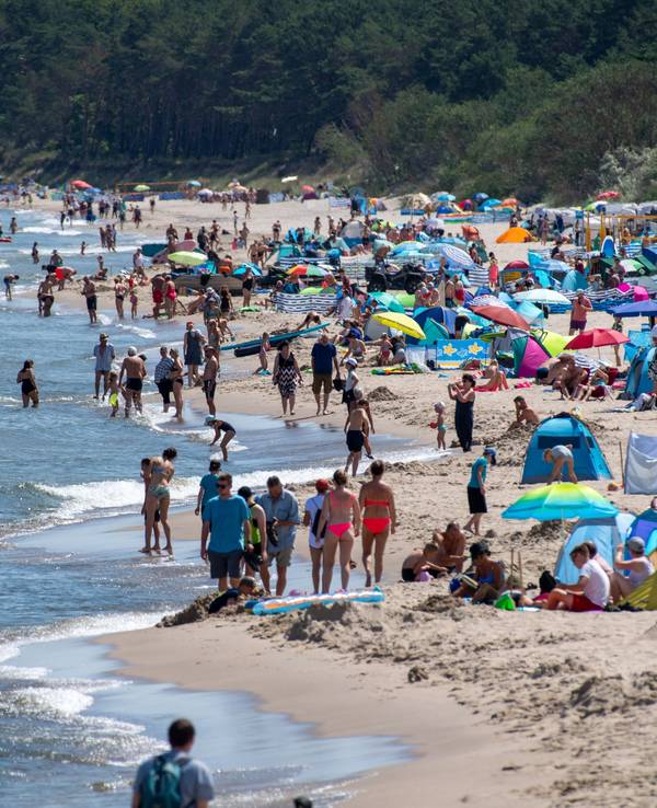Zahlreiche Menschen sind bei sonnigem Wetter am Strand der Insel Usedom unterwegs.