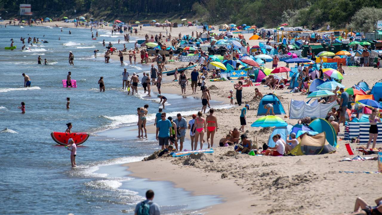 Zahlreiche Menschen sind bei sonnigem Wetter am Strand der Insel Usedom unterwegs.