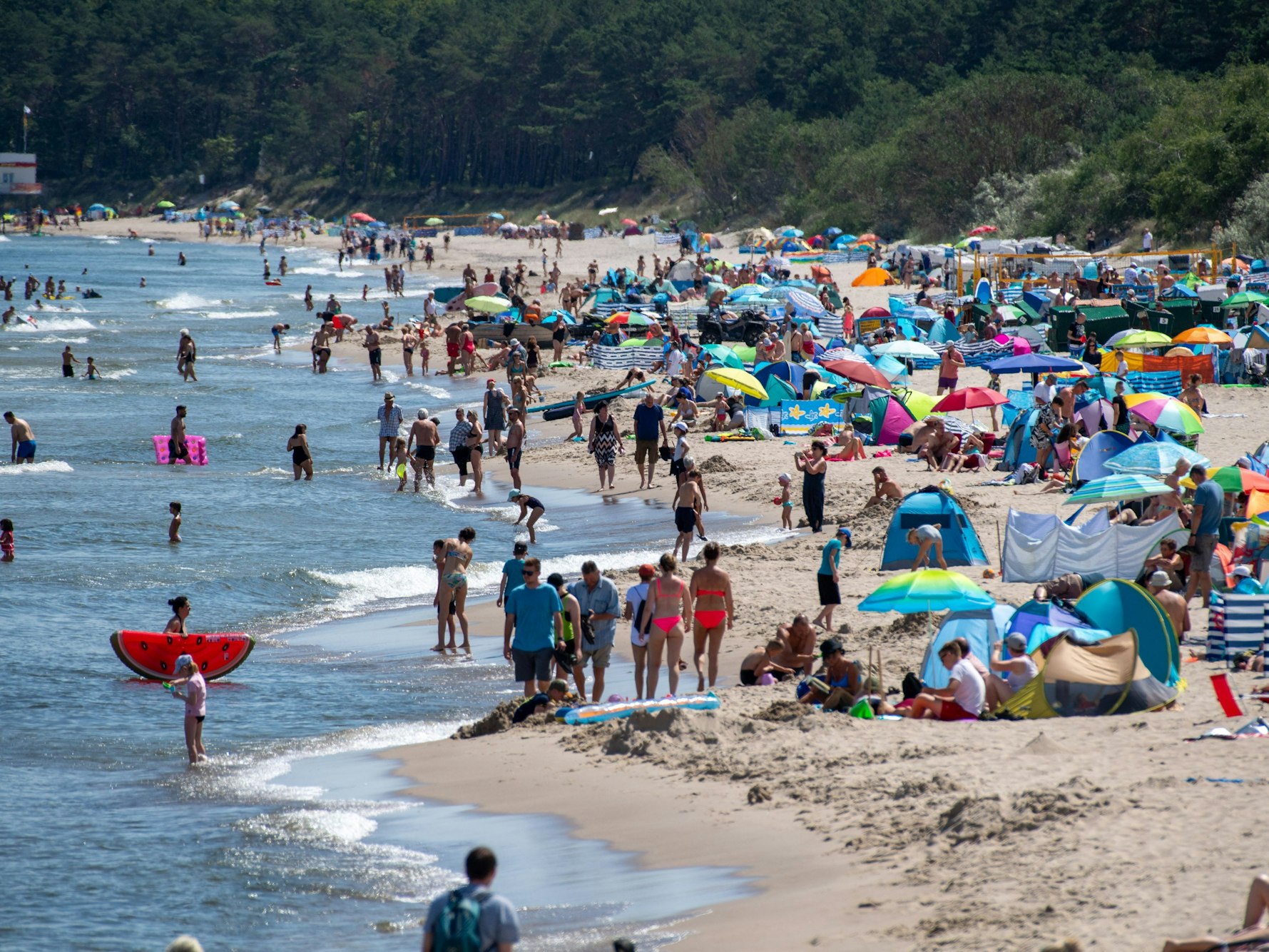 Zahlreiche Menschen sind bei sonnigem Wetter am Strand der Insel Usedom unterwegs.