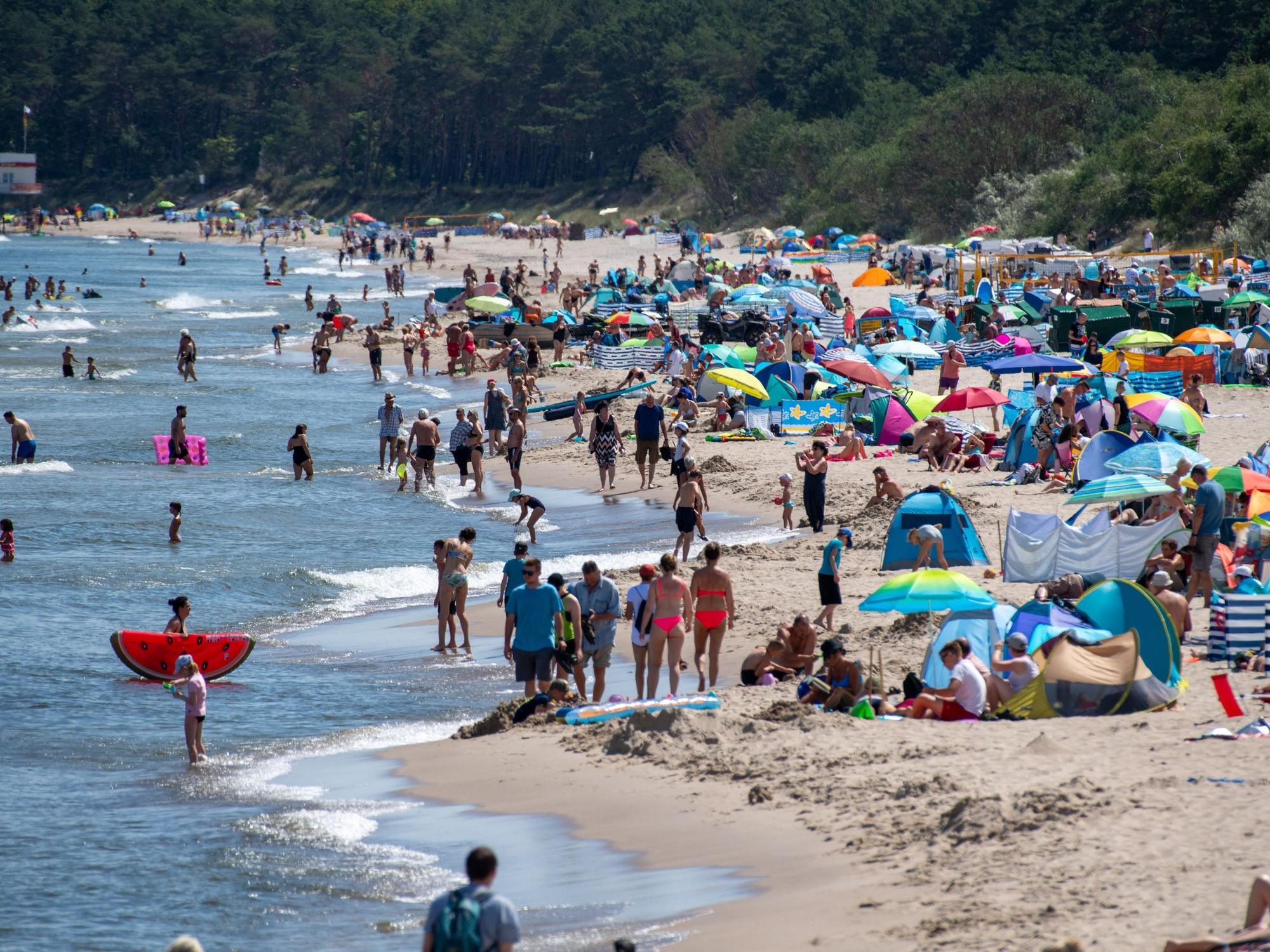 Zahlreiche Menschen sind bei sonnigem Wetter am Strand der Insel Usedom unterwegs.