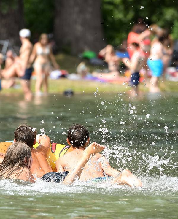 Jugendliche baden mit einem Schwimmring im Englischen Garten im Eisbach.