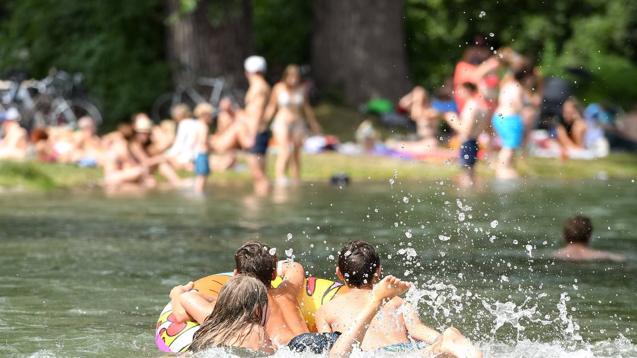 Jugendliche baden mit einem Schwimmring im Englischen Garten im Eisbach.