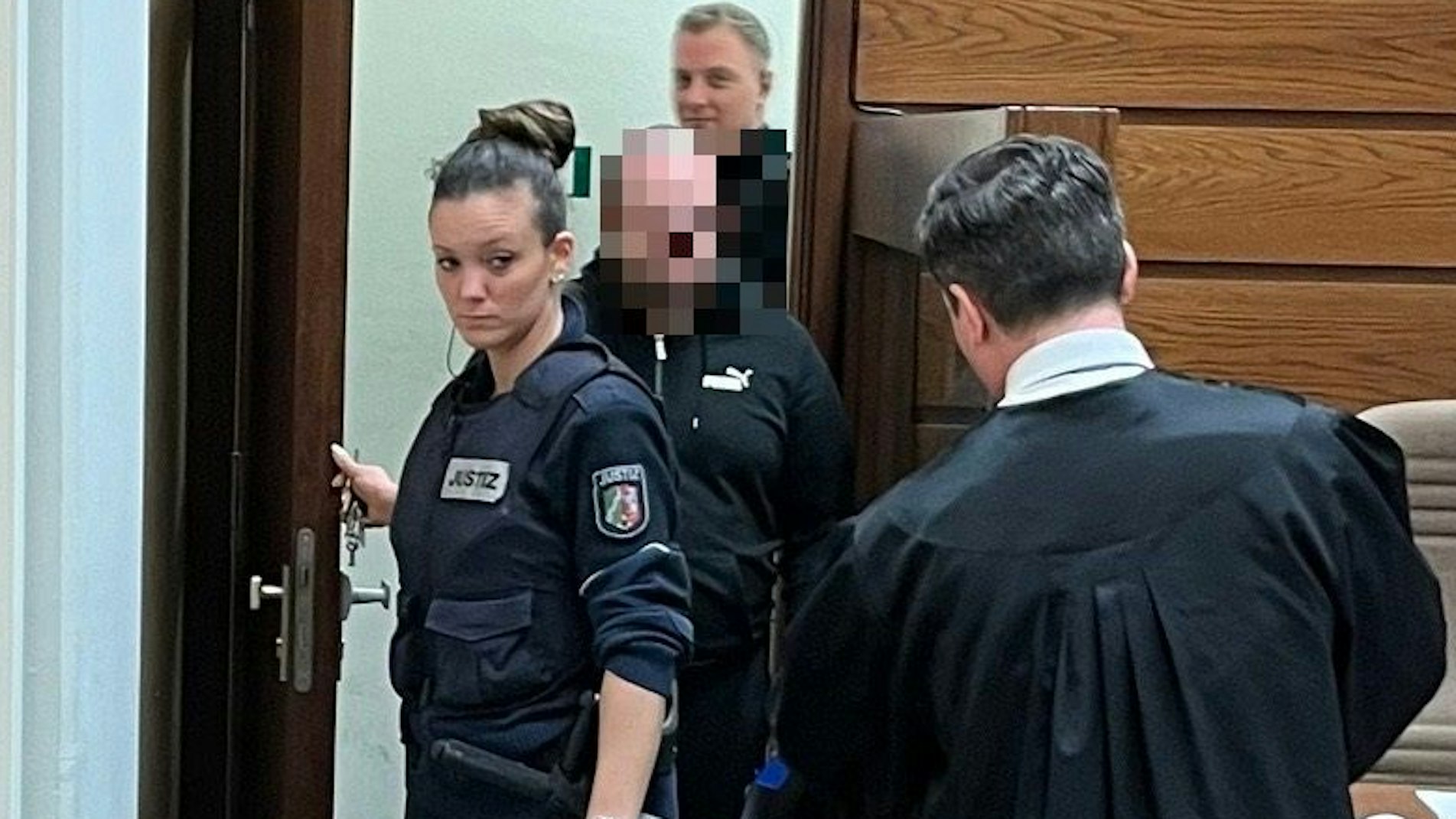 Der 24-jährige Angeklagte betritt den Gerichtssaal neben Beamten.