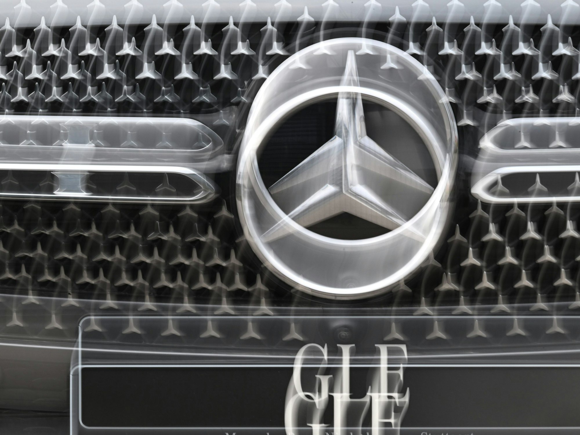 Das Logo der Automarke Mercedes-Benz ist an der Front eines Mercedes-Benz Fahrzeugs angebracht (Wischeffekt durch Langzeitbelichtung und Zoomen).