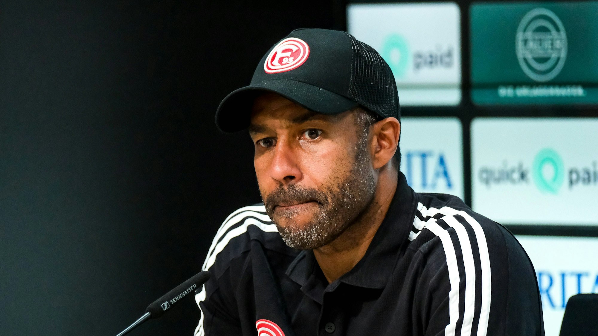 Fortuna Düsseldorfs Trainer Daniel Thioune sitzt bei der Pressekonferenz nach dem Spiel bei Wehen Wiesbaden auf dem Podium.