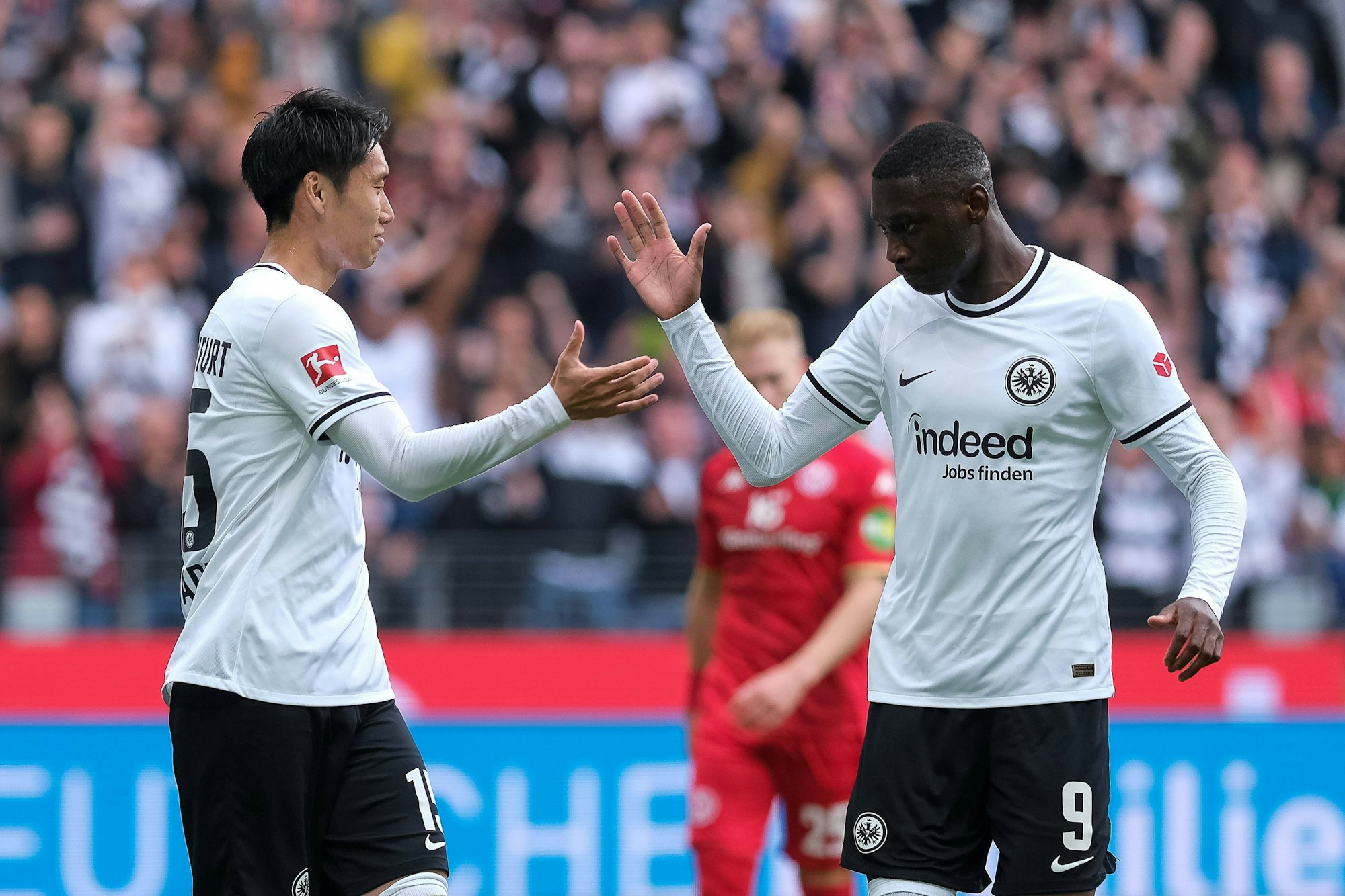 Daichi Kamada (l.) und Kolo Muani klatschen sich ab.