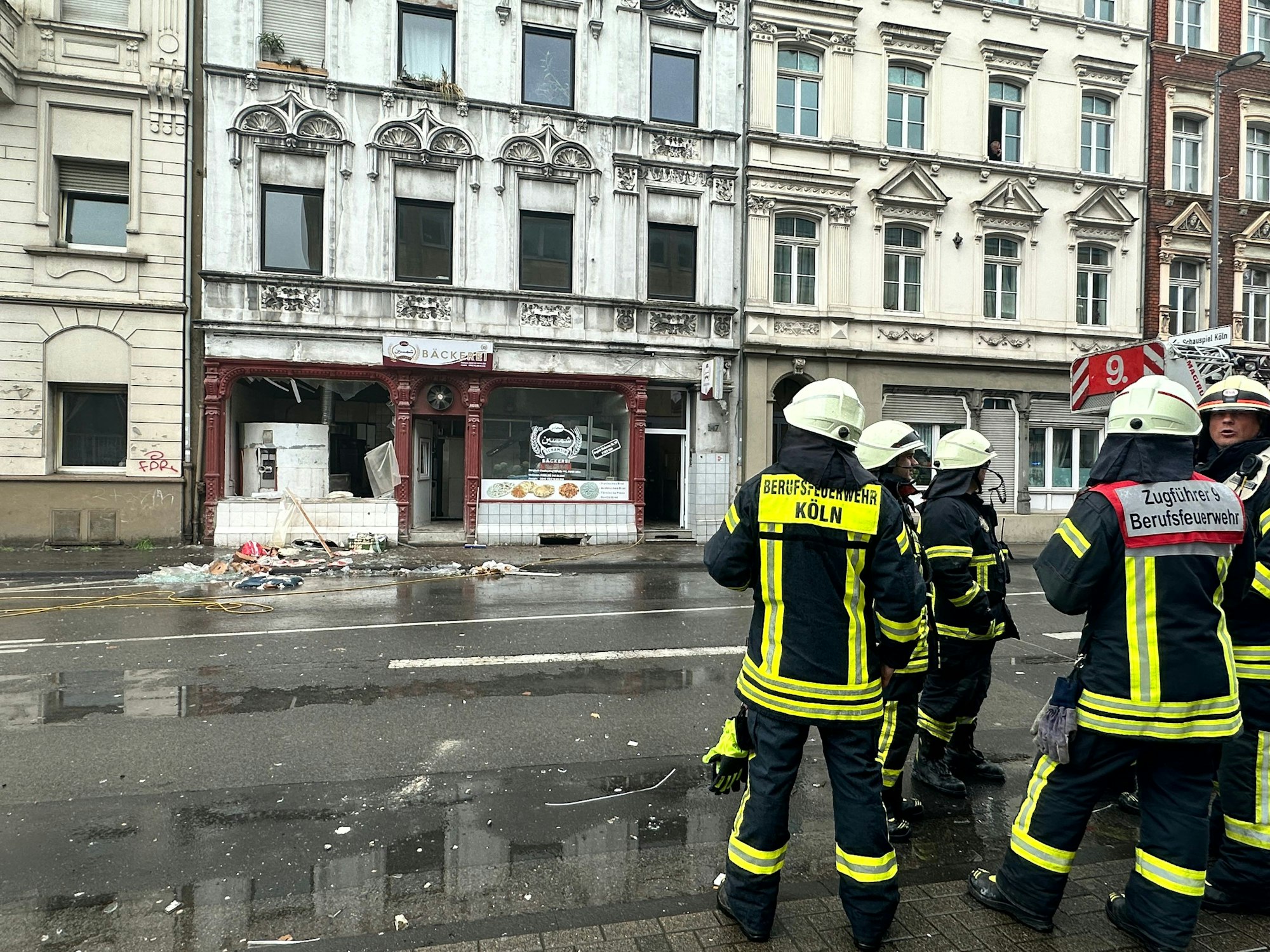 Einsatzkräfte stehen vor einer Bäckerei an der Bergisch Gladbacher Straße, in der es am (19. April 2024) zu der Verpuffung gekommen ist.