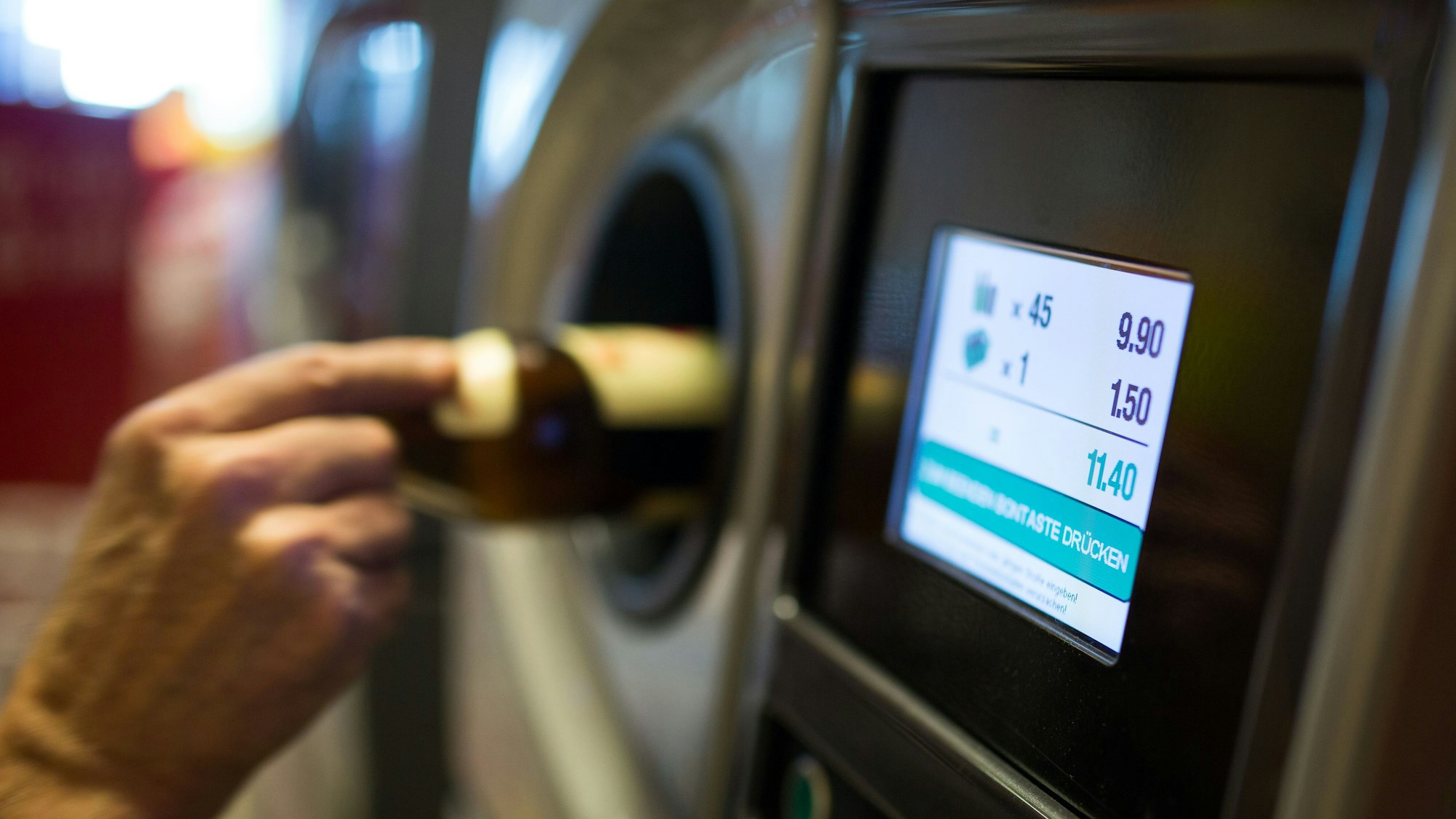 Eine Person gibt Pfandflaschen an einem Automaten ab.