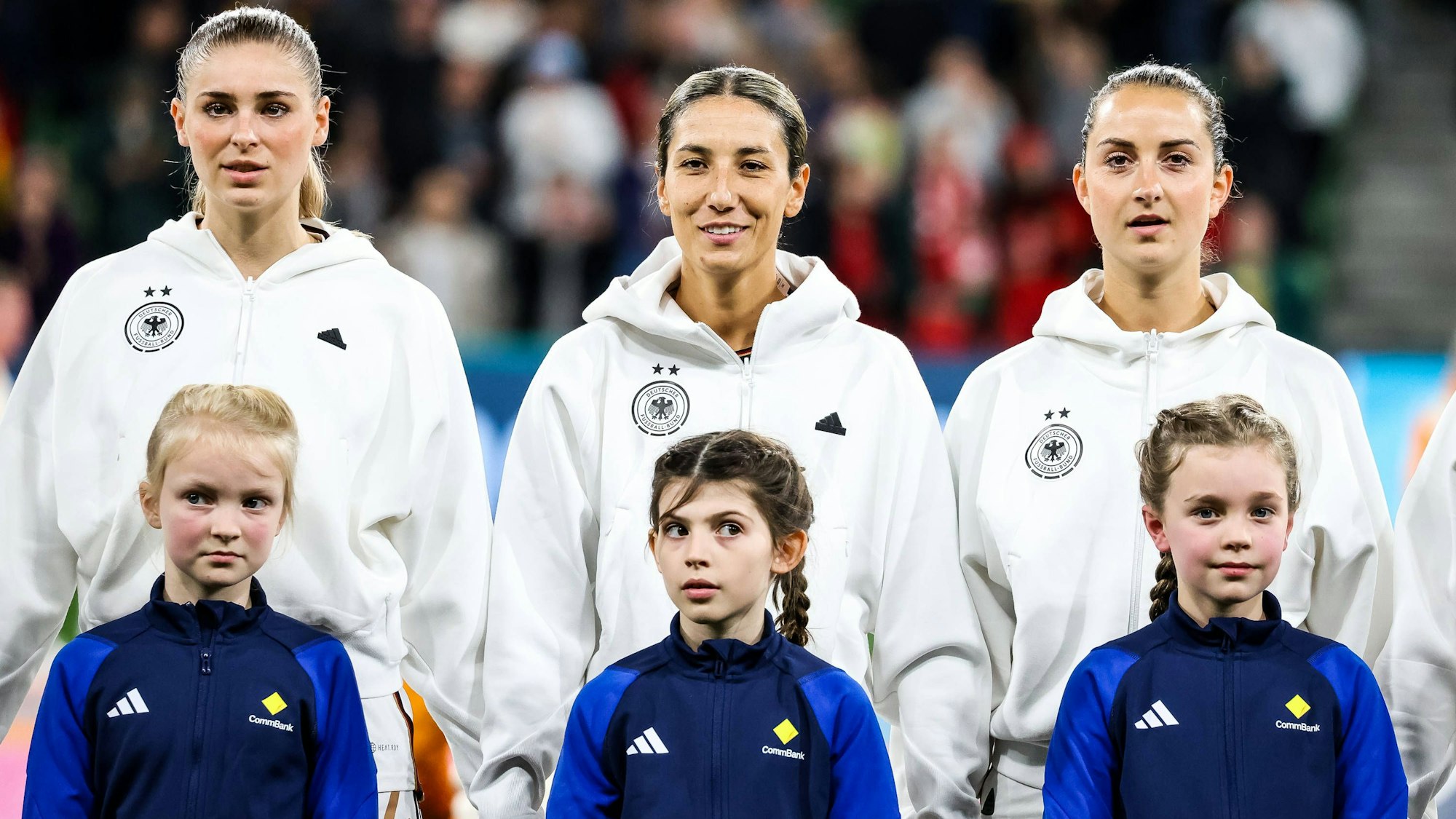 Jule Brand (l.), Sara Doorsoun (M.) und Sara Däbritz stehen kurz vor dem Anpfiff nebeneinander auf dem Platz.