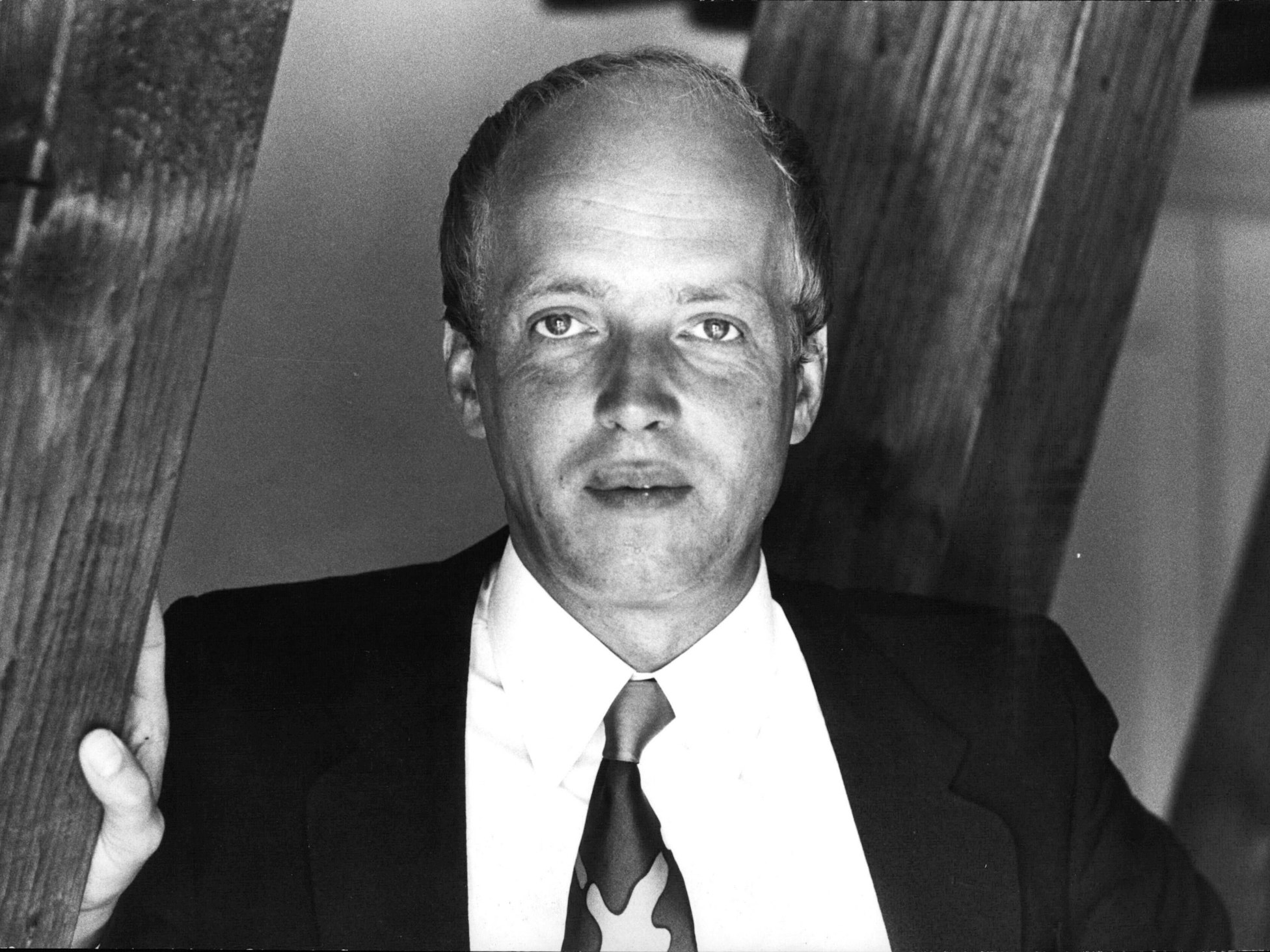 Altes Foto von Dr. Renatus Rüger, der sich an einem Holzbalken festhält.