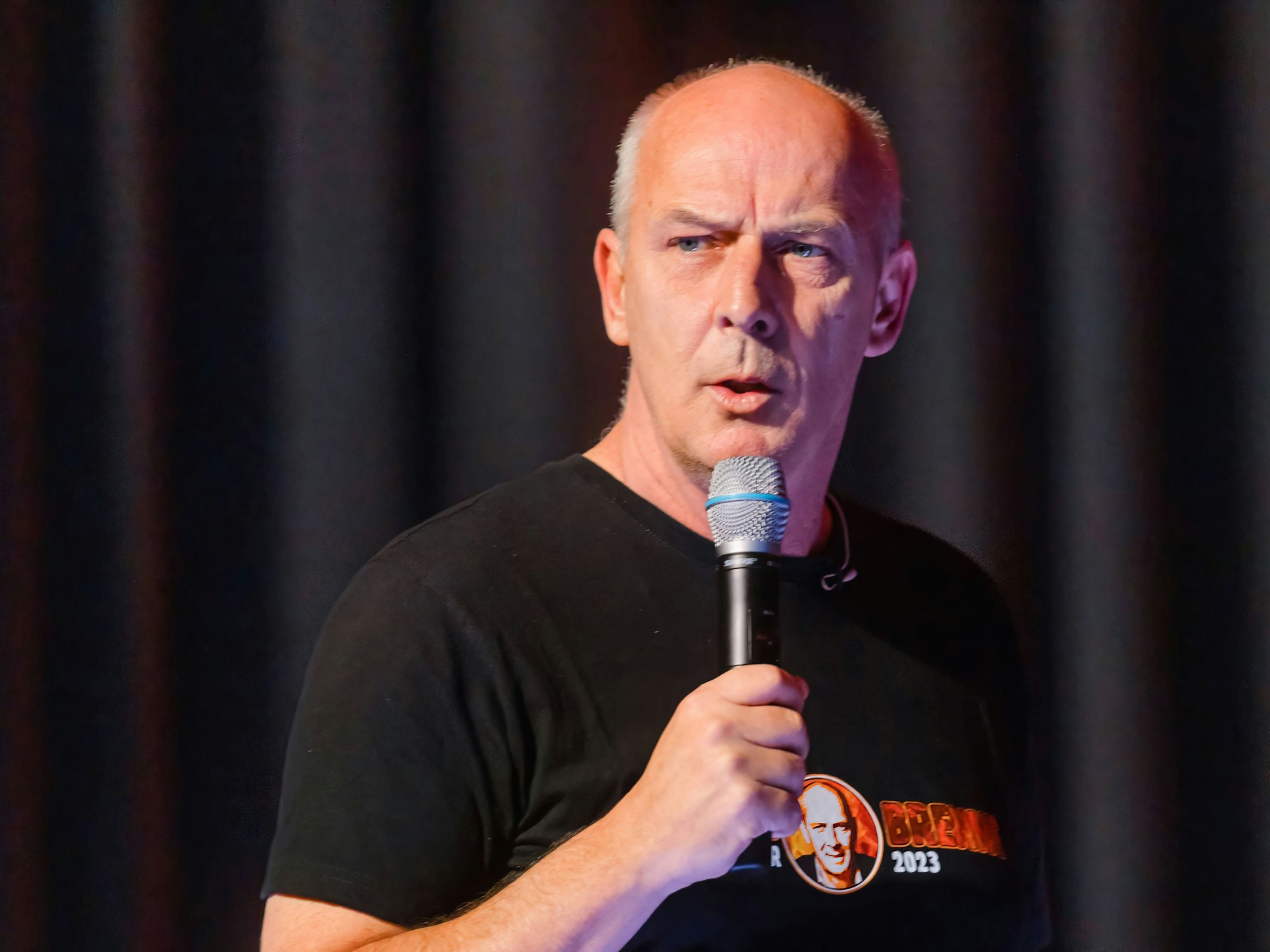 Mario Basler spricht auf einer Bühne in ein Mikrofon.