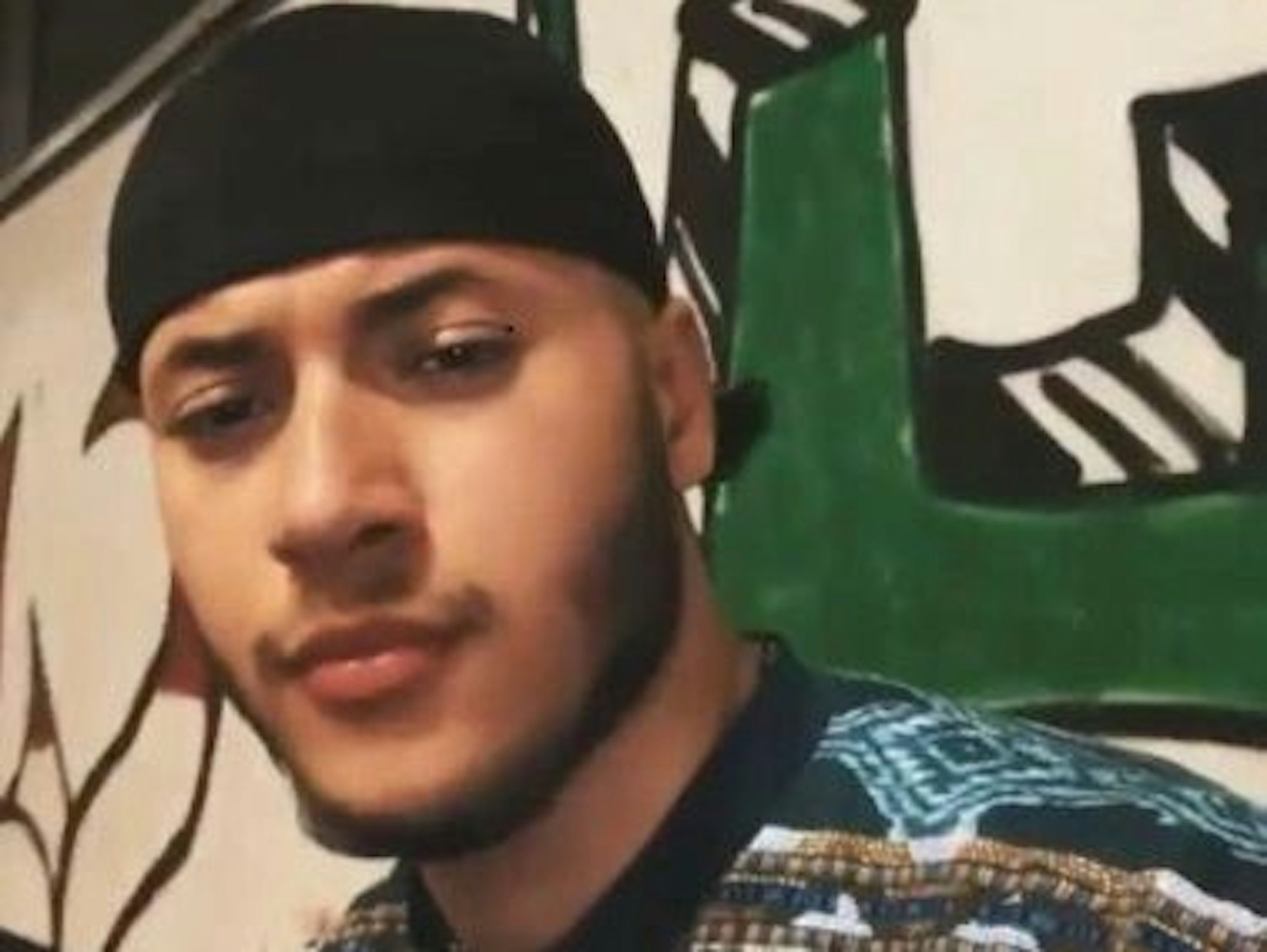 Ein junger Mann mit leichtem Bart und Tuch auf dem Kopf guckt in die Kamera.