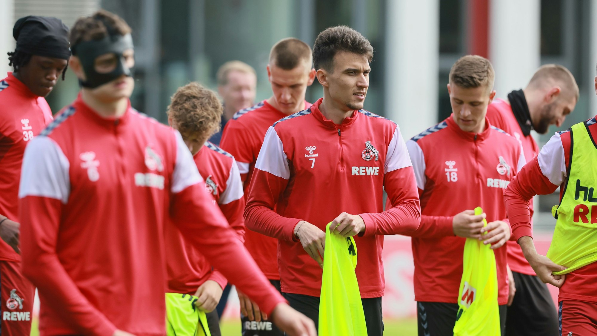 Die FC-Profis ziehen sich beim Training am Geißbockheim Leibchen an.