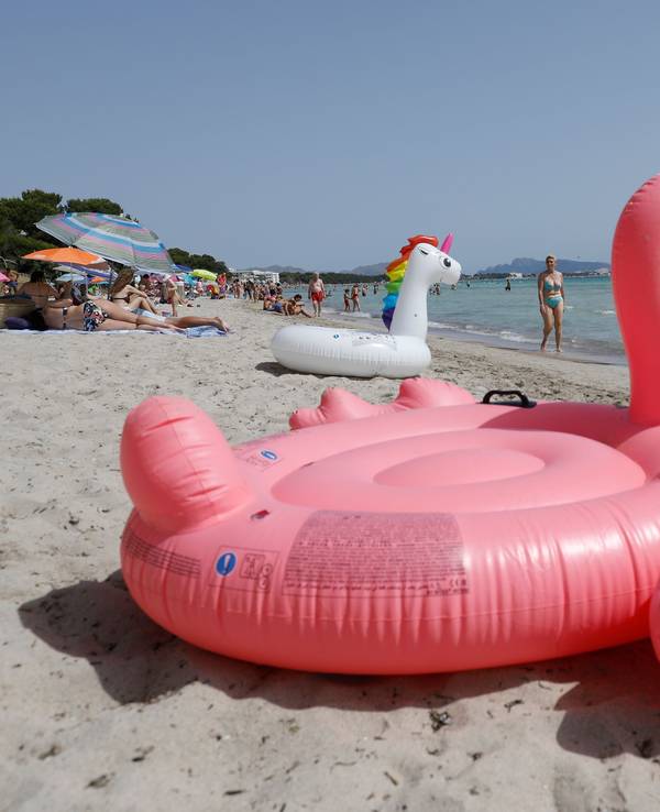 Ein aufblasbarer rosa Flamingo liegt am Strand von Playa de Muro im Norden von Mallorca.
