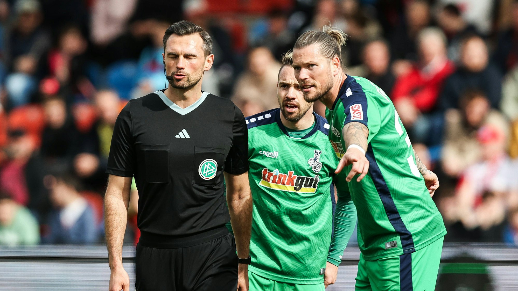Die Duisburg-Profis Daniel Ginczek und Thomas Pledl diskutieren im Spiel bei der SpVgg Unterhaching mit dem Schiedsrichter.