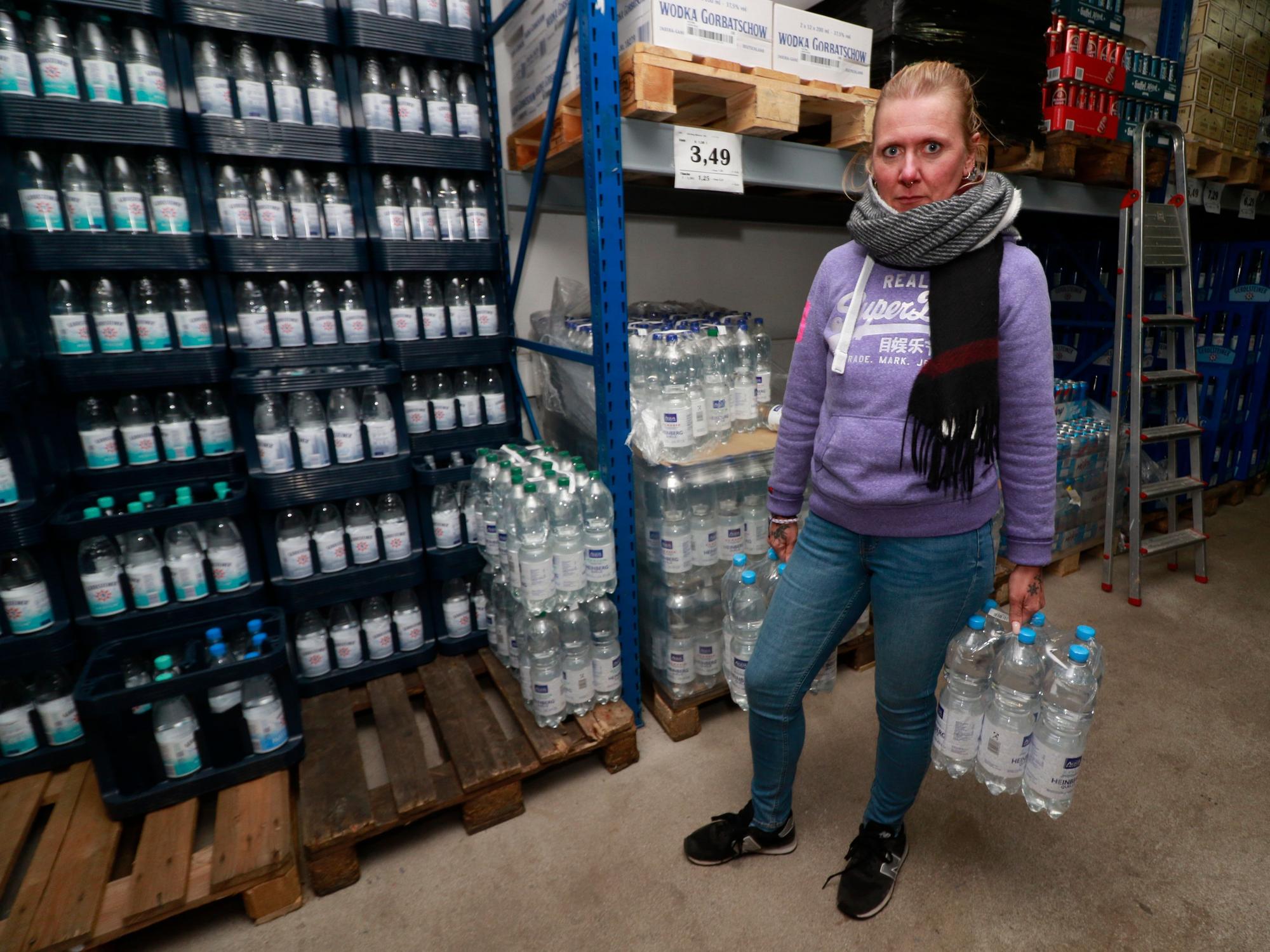 Eine Frau mit zwei Packungen Wasser in den Händen.
